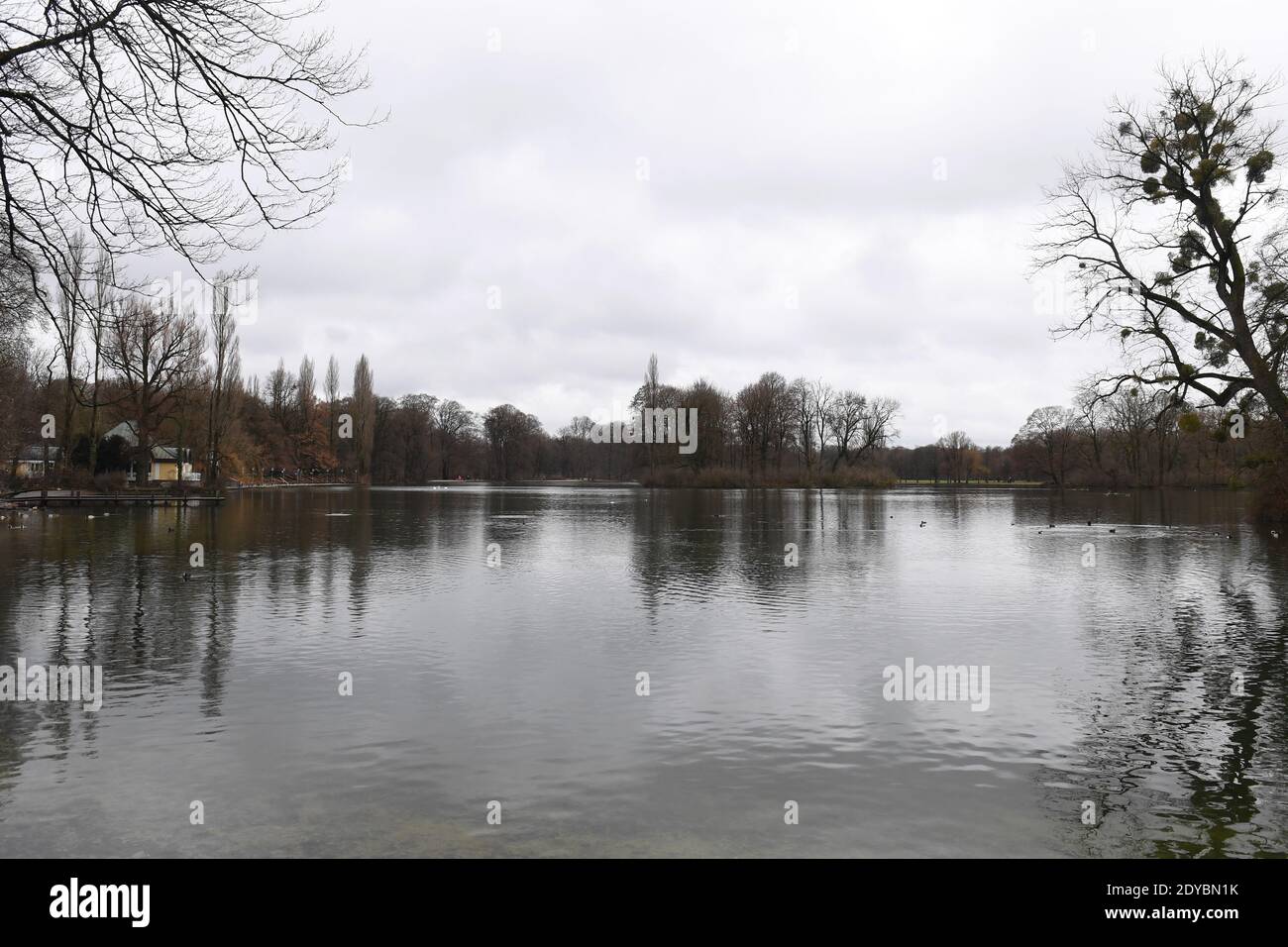 Munich, Germany. 25th Dec, 2020. The Seehaus (l) is seen at Kleinhesseloher See in the English Garden. Overcast skies and light rain with light snowfall is prevalent in the state capital. Credit: Felix Hörhager/dpa/Alamy Live News Stock Photo