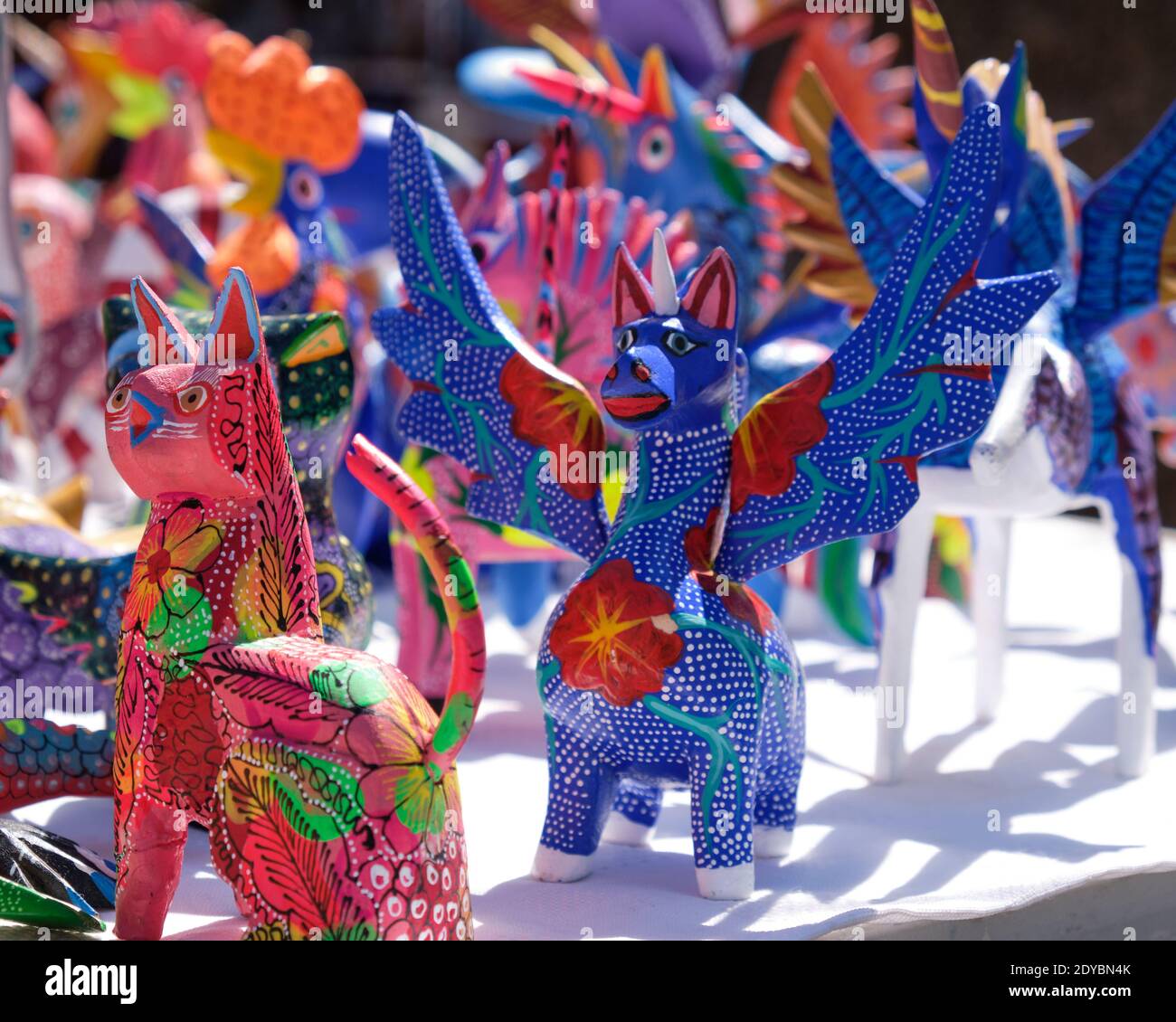 An Alebrijes, whimsical carvings depicting an imaginary winged creatures painted with intense colors and intricate patterns on Market table in Mexico Stock Photo