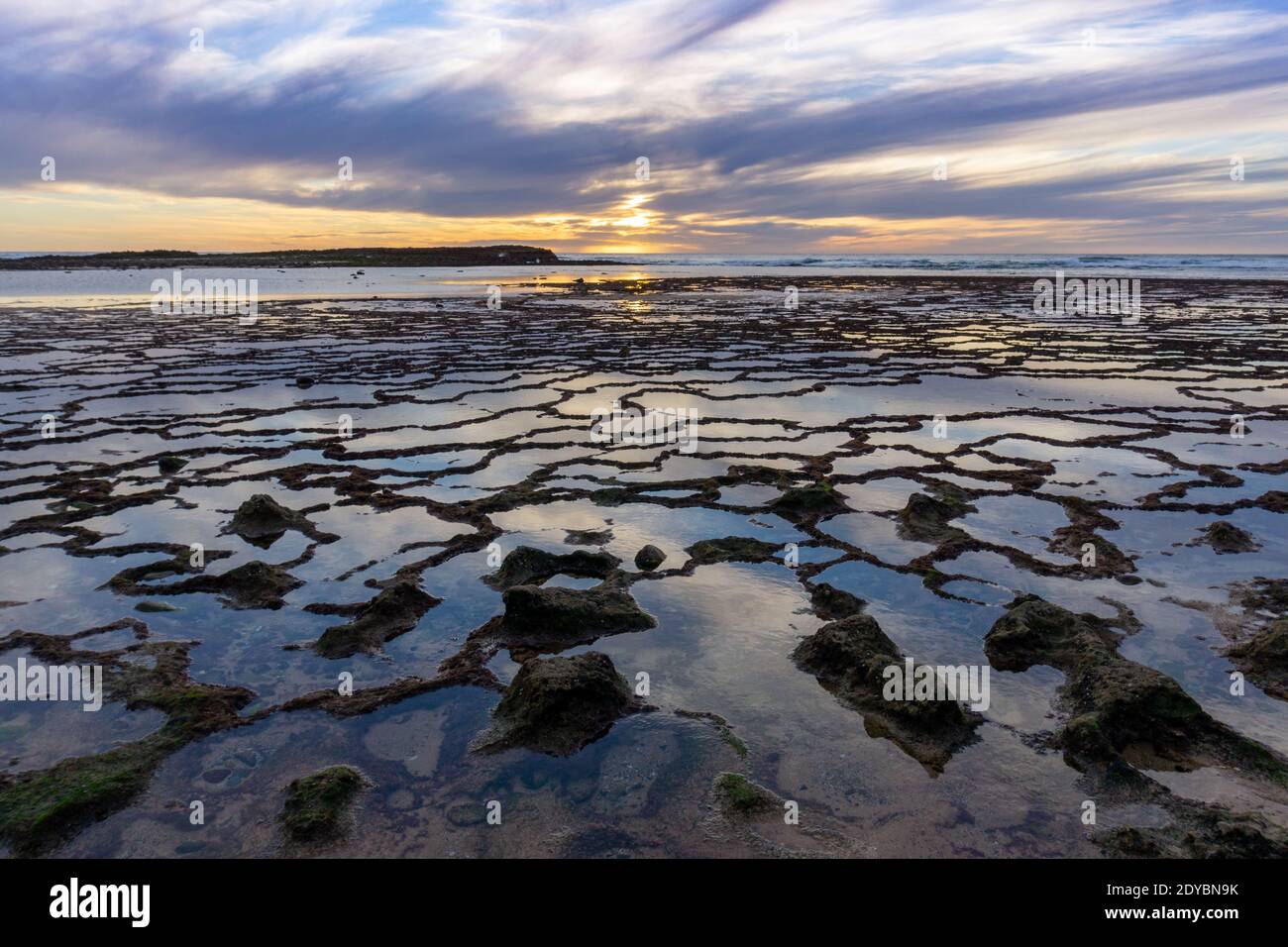 A beautiful sunset over the ocean with rocky beach and tidal pools in ...