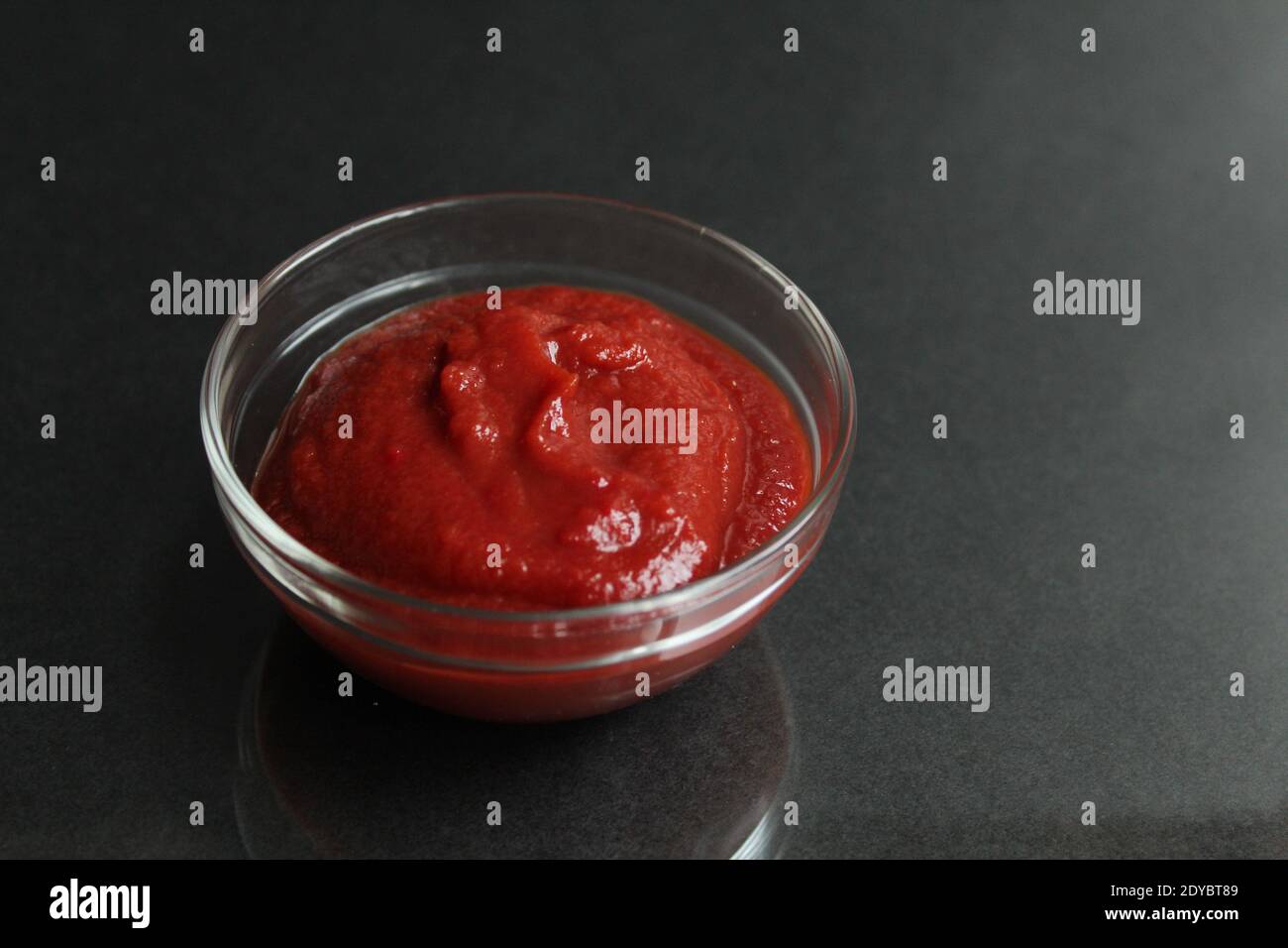 red tomato sauce paste in a glass sauce bowl on a black background copy space place for text. Stock Photo