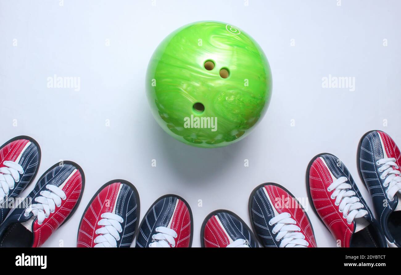 Indoor family sports. Many bowling shoes and bowling ball on white background. Top view. Minimalism Stock Photo