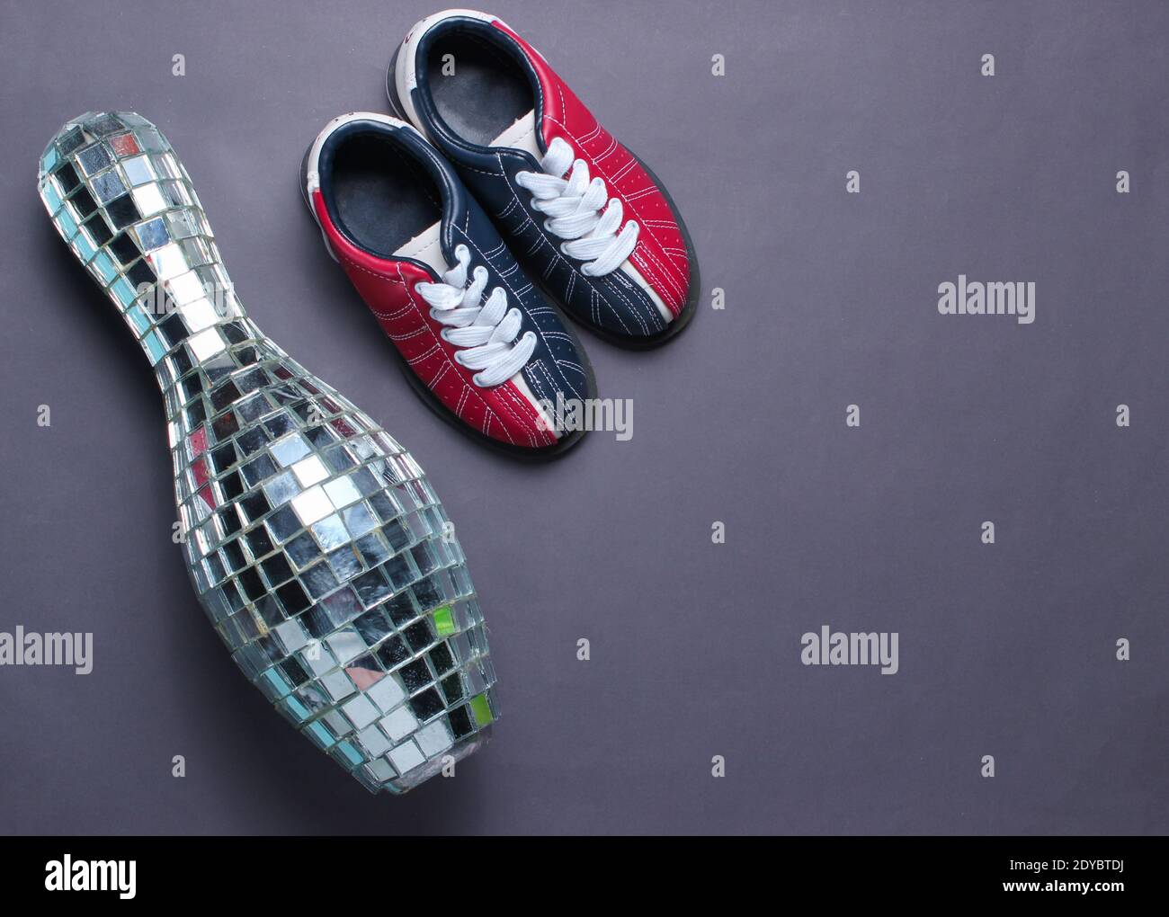 Disco mirror skittles, children's bowling shoes on gray background. Top