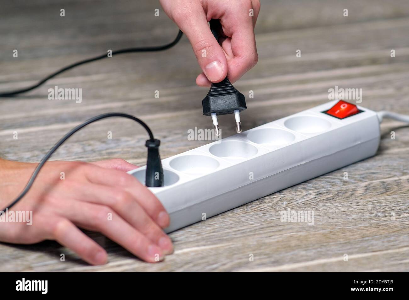 The hostess holds in her hand an electric extension cord with a fuse and connect the appliance to the outlet Stock Photo