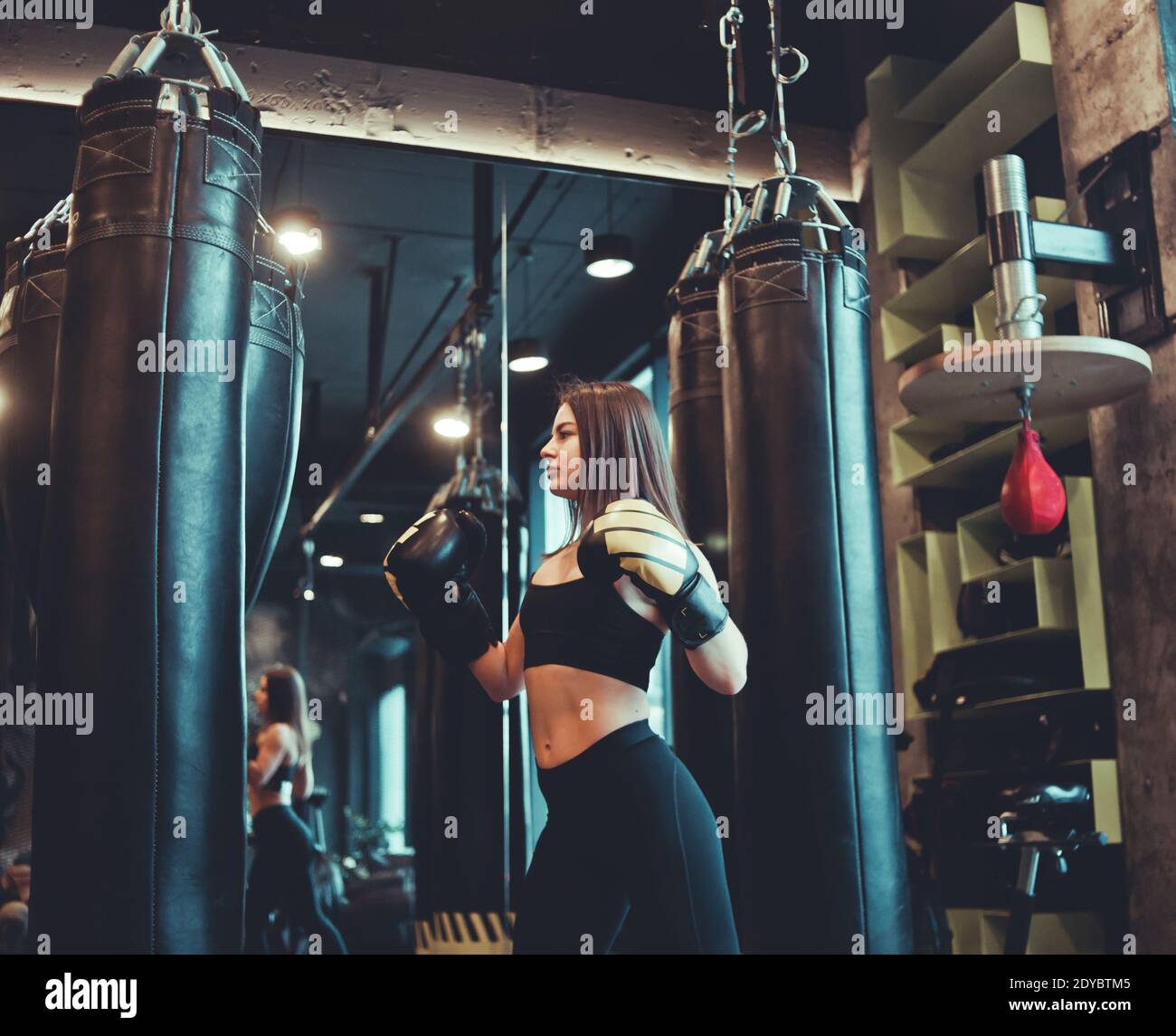 Fit Girl In Sportswear And Boxing Gloves Trains Blow Against A Punching Bag In A Dark Gym Women S Self Defense Training The Ability To Pinch Yoursel Stock Photo Alamy