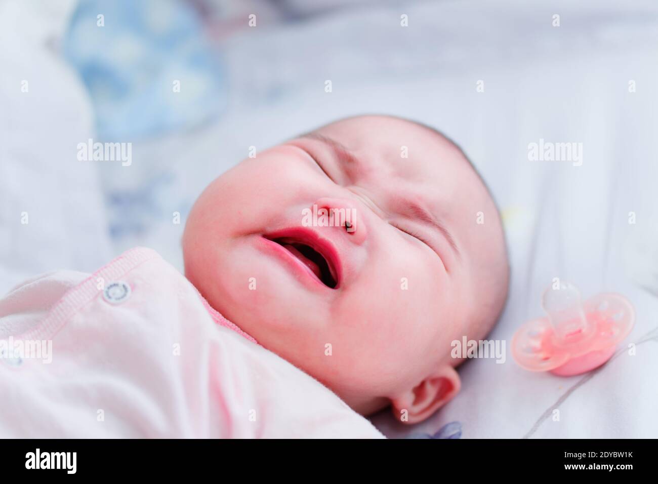 Four month old Chinese baby girl crying in bed. Stock Photo