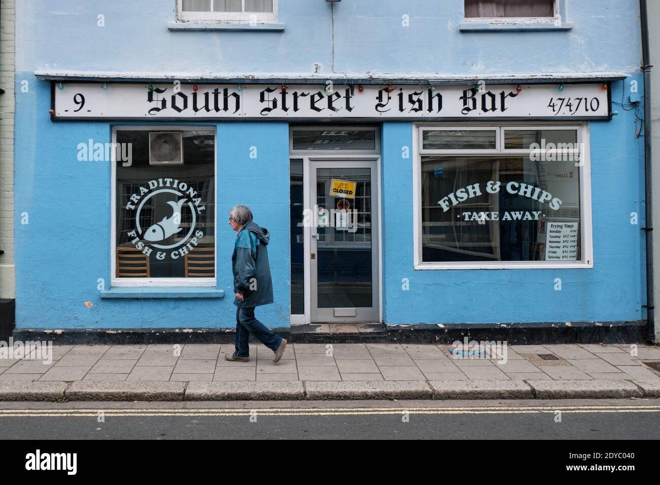 South Street Fish Bar, a blue fish a chips shop in Lewes, England, with pedestrian walking by in autumn Stock Photo