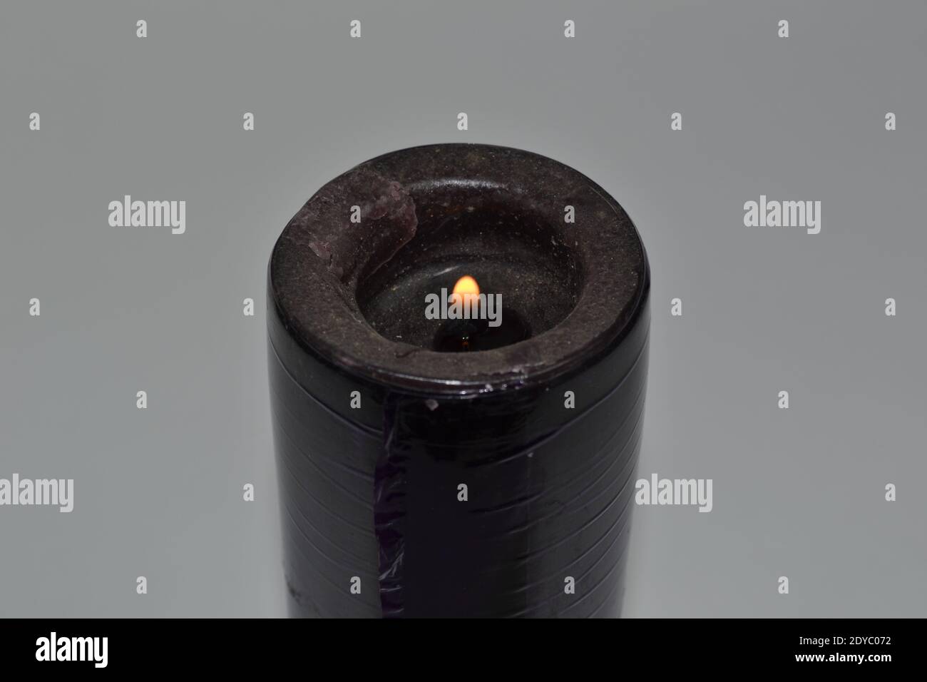 A closeup shot of a black burning candle isolated on a gray background ...