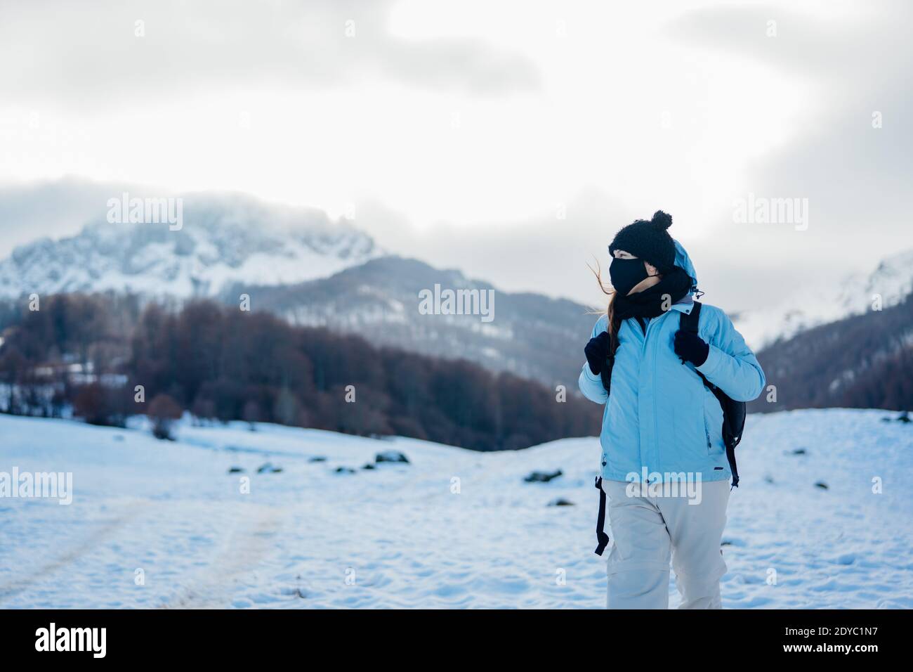 Female tourist wearing a protective mask in nature on mountain holiday vacation.Active vacation during the pandemic.Natural beauty.Hiker on a winter t Stock Photo