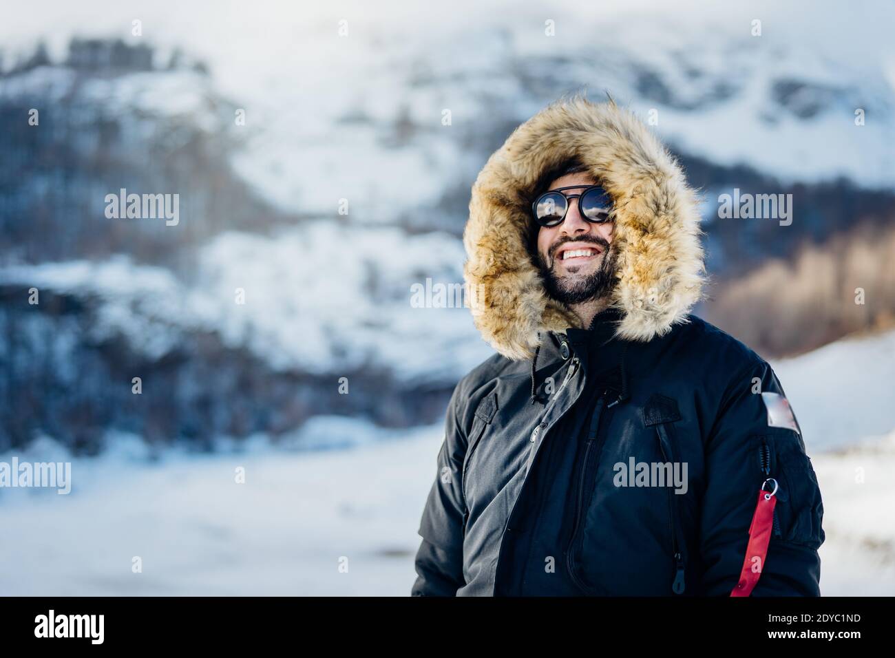 Happy male tourist smiling in nature on a mountain during an active holiday vacation.Hiker on a winter trek.Ski season, extreme snow sport adventure. Stock Photo