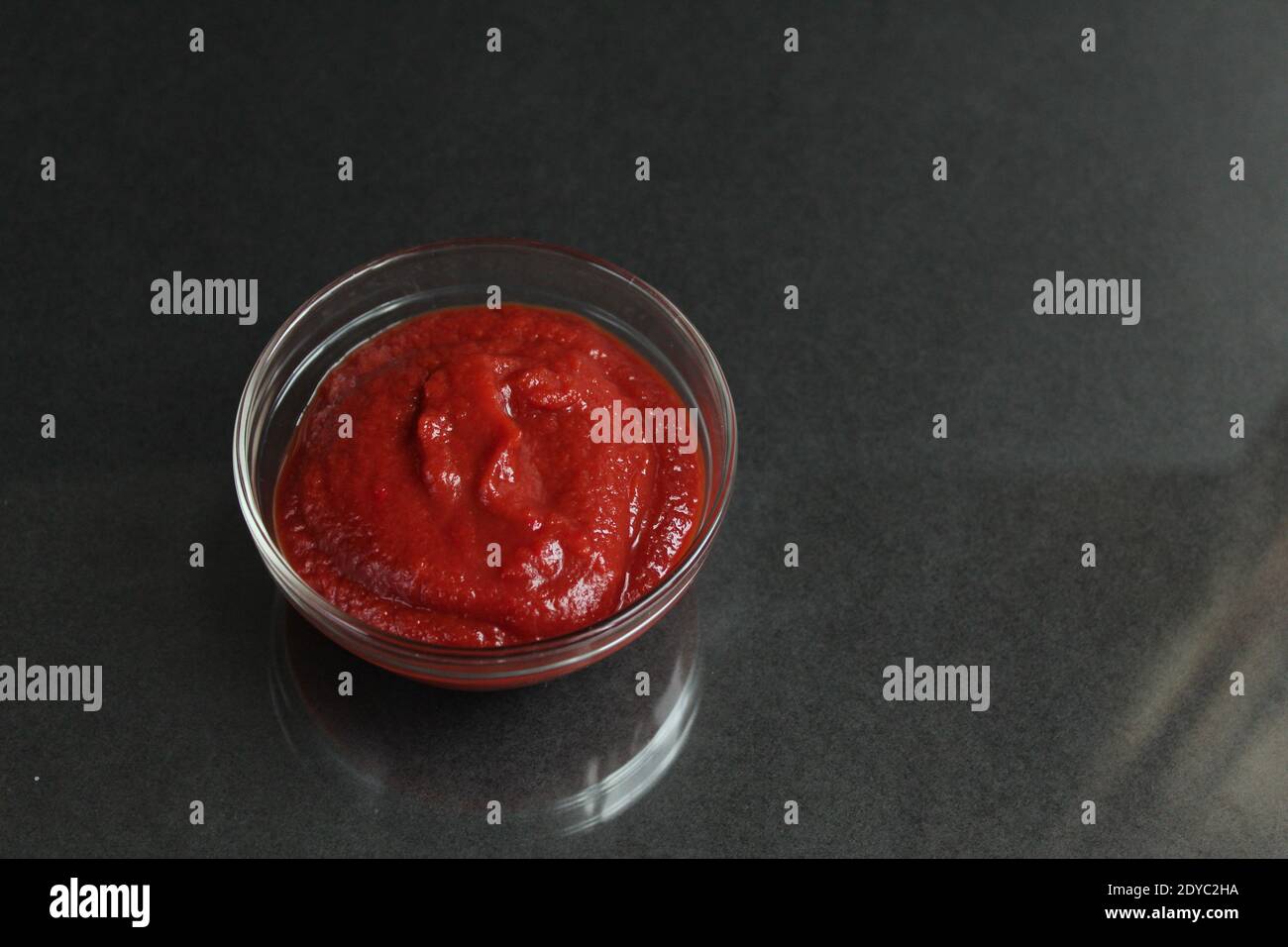 red tomato sauce paste in a glass sauce bowl on a black background copy space place for text. Stock Photo