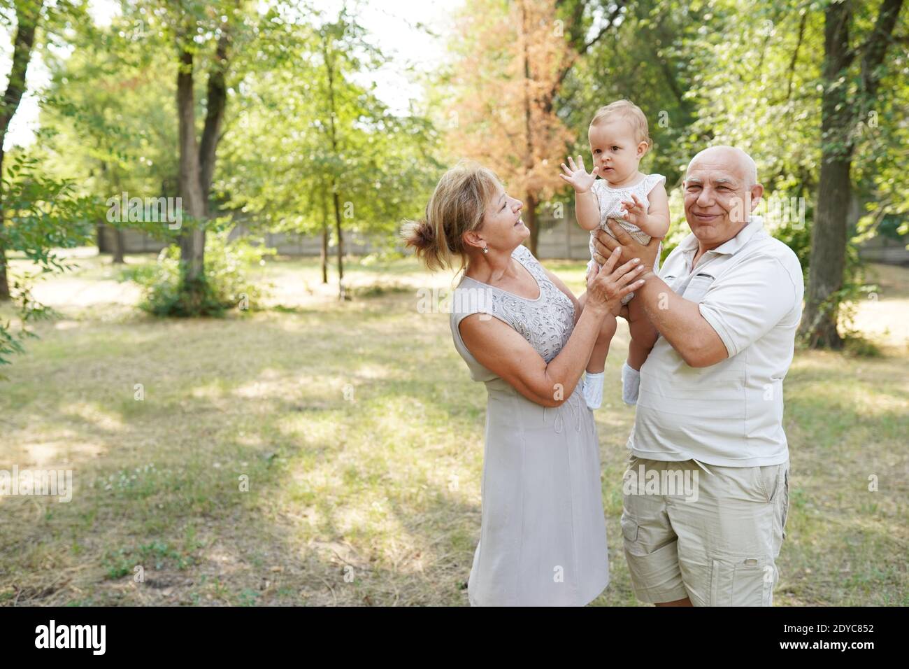 grandparents and baby grandchild walking in nature park, copy space Stock Photo