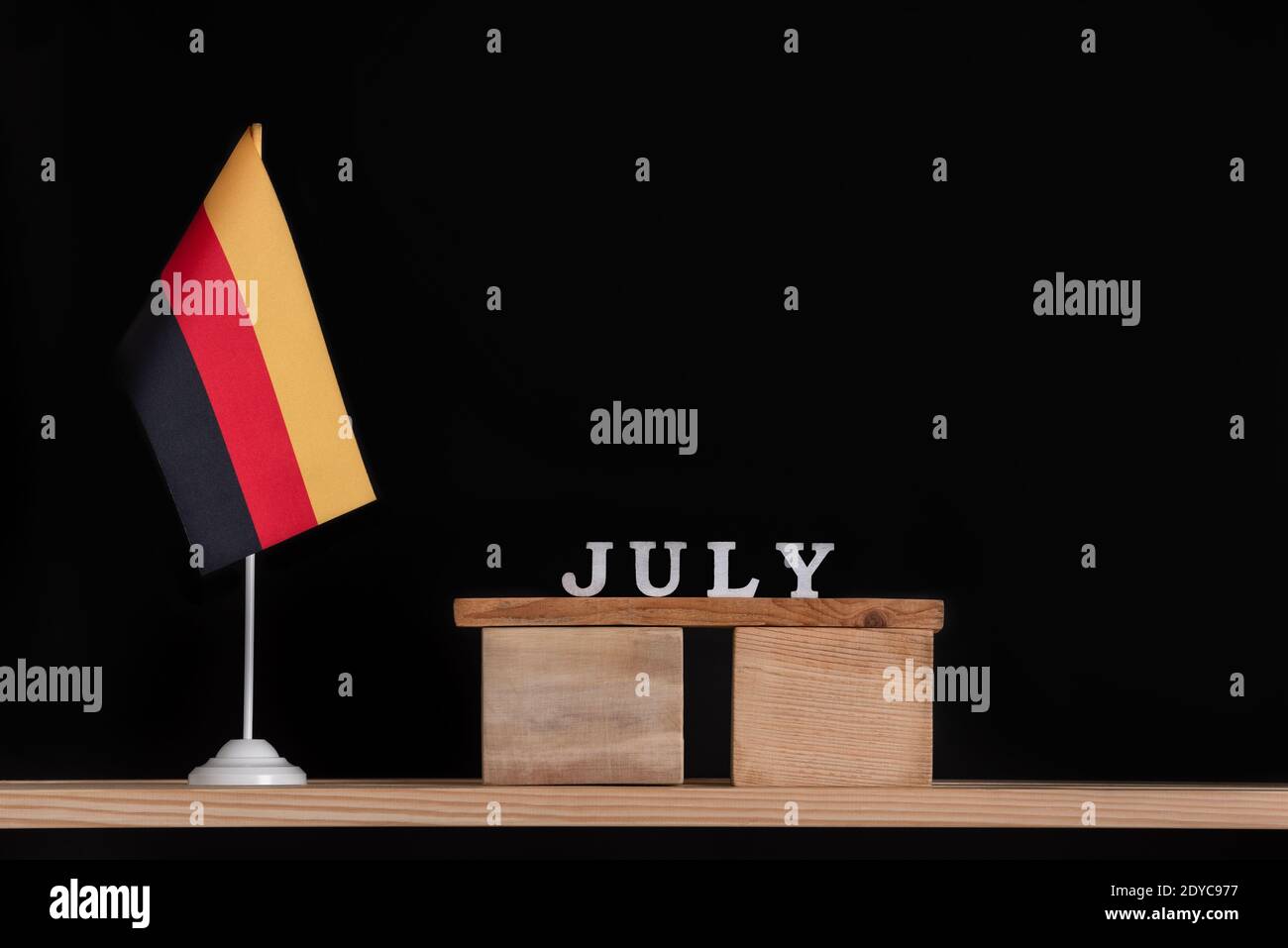 Wooden calendar of July with table German flag on black background ...