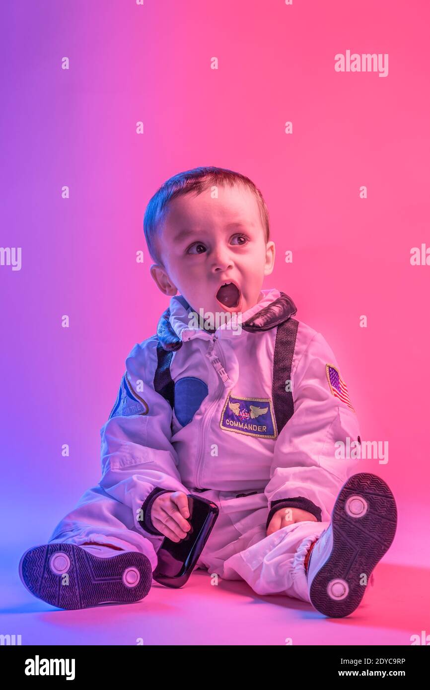 Colorful portrait of a  little boy  wearing american astronaut clothes,  illuminated with red and blue light. astronaut and children concept. Stock Photo