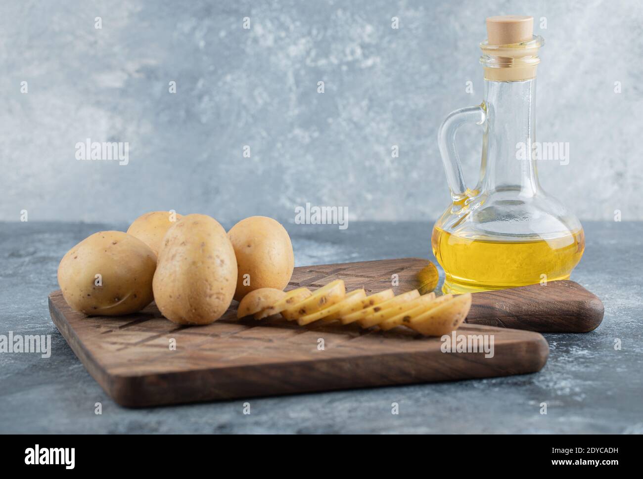 Sliced and whole potatoes on the wooden cutting board Stock Photo