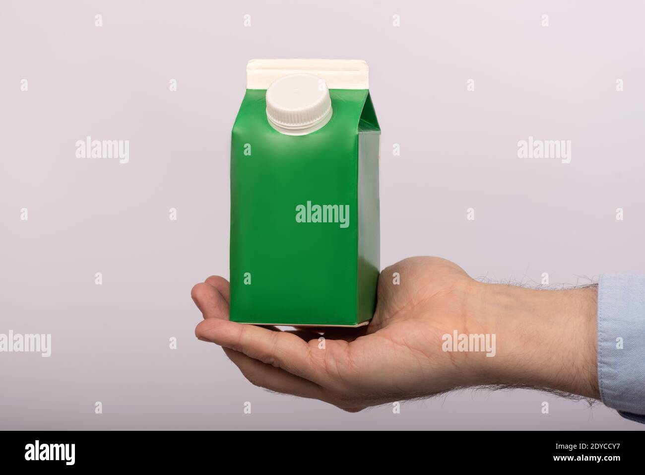 Green paper bag in mans hand on white background. Juice yogurt milk