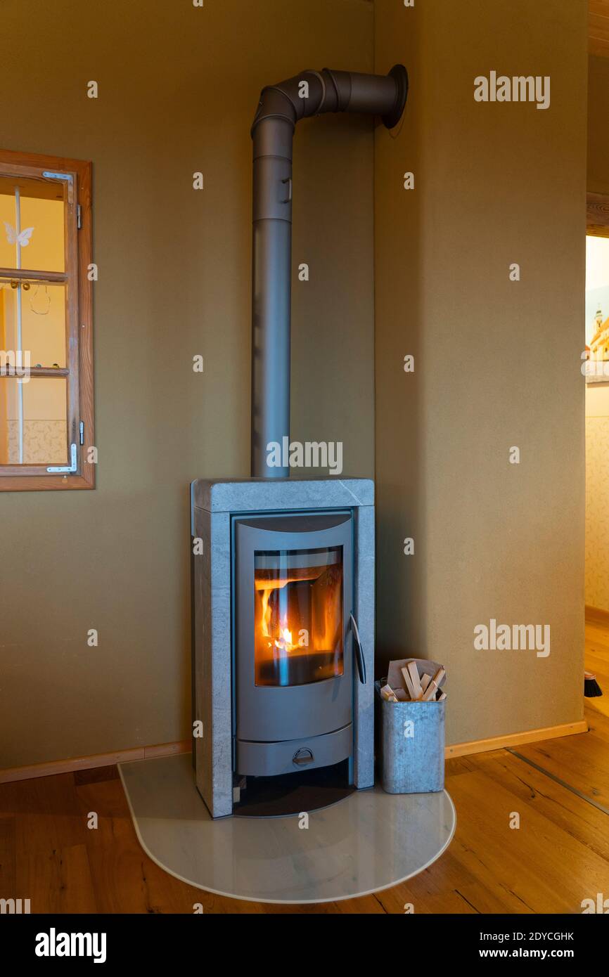 Traditional freestanding wood burning ovens (known as a Schwedenofen or Kaminofen), particularly with a stone surround, are very popular in Austria Stock Photo