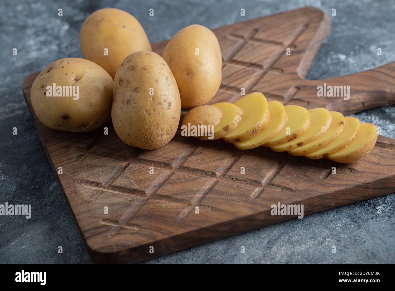 Close up photo of organic potatoes on wooden cutting board Stock Photo
