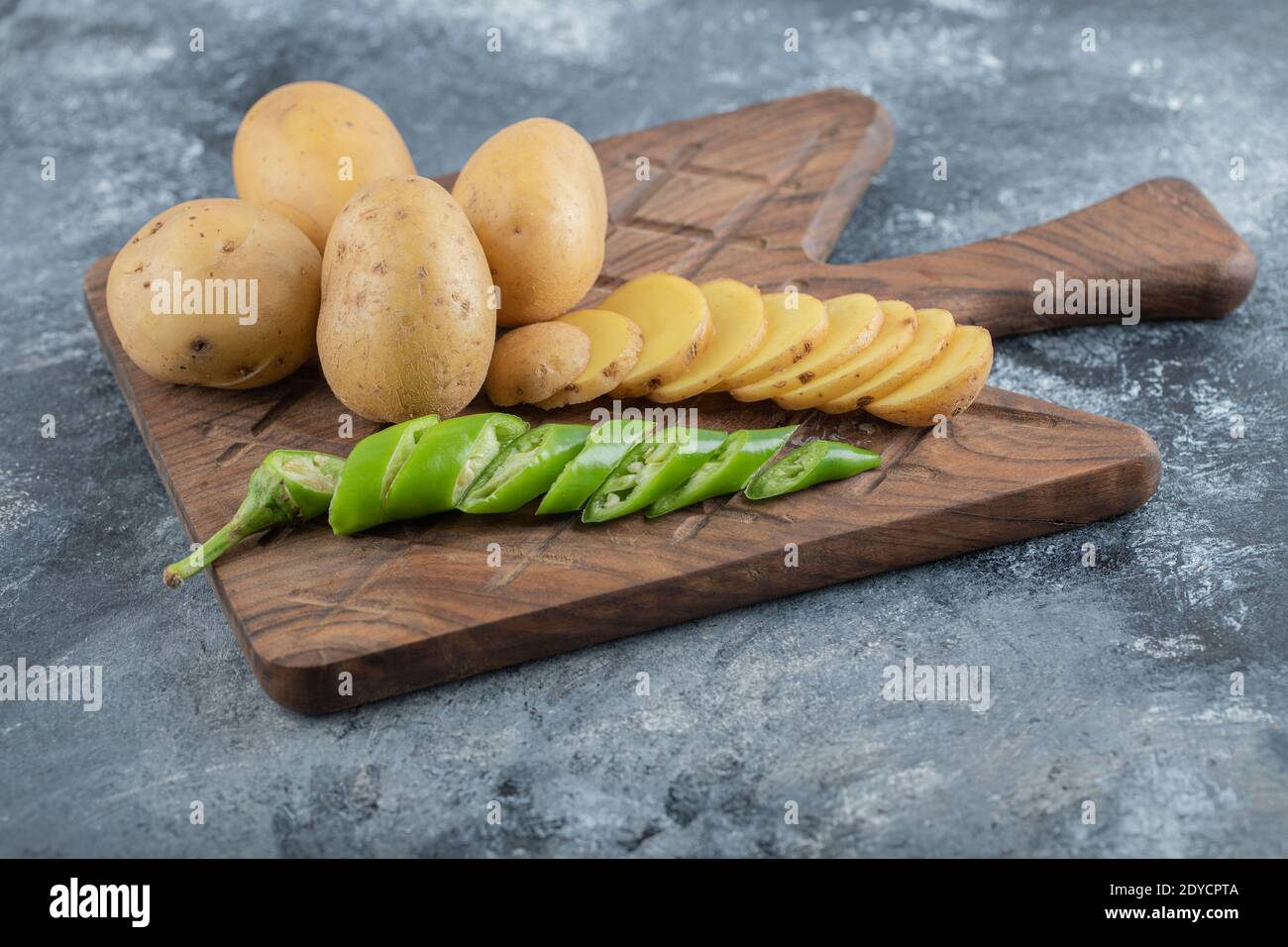 Man pouring salt over the sliced potatoes Stock Photo