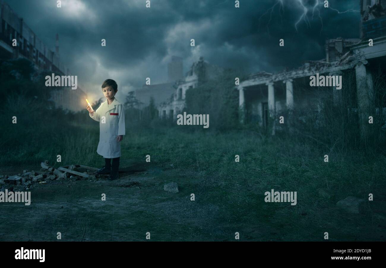 Scientist boy holding a syringe with the cure for the pandemic (Corona - Covid-19) in an apocalyptic scenario with destroyed buildings Stock Photo