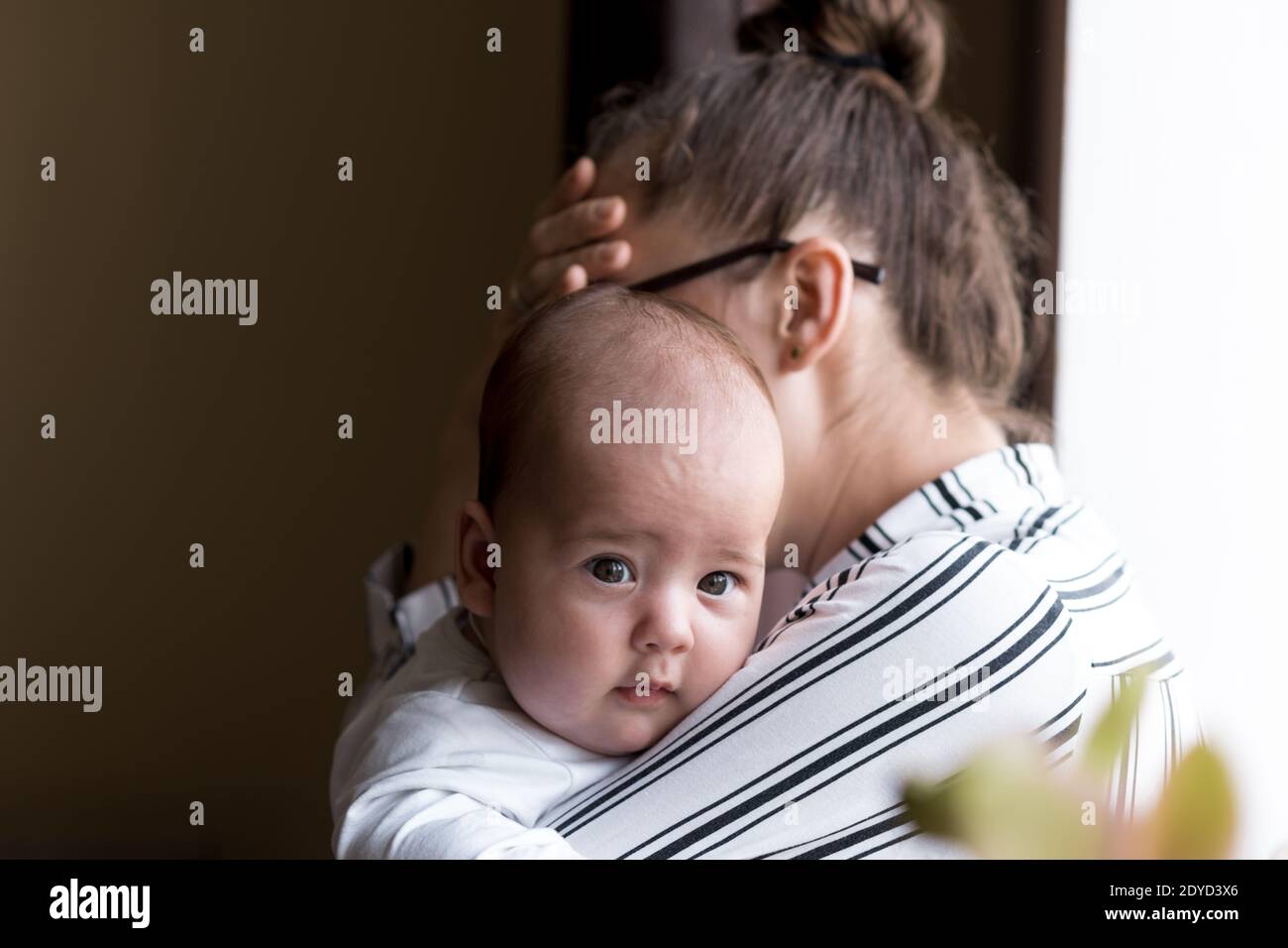Childhood, motherhood, illness family concepts - upset, tired nervous business woman Lady mother with headache holding infant child newborn baby in Stock Photo
