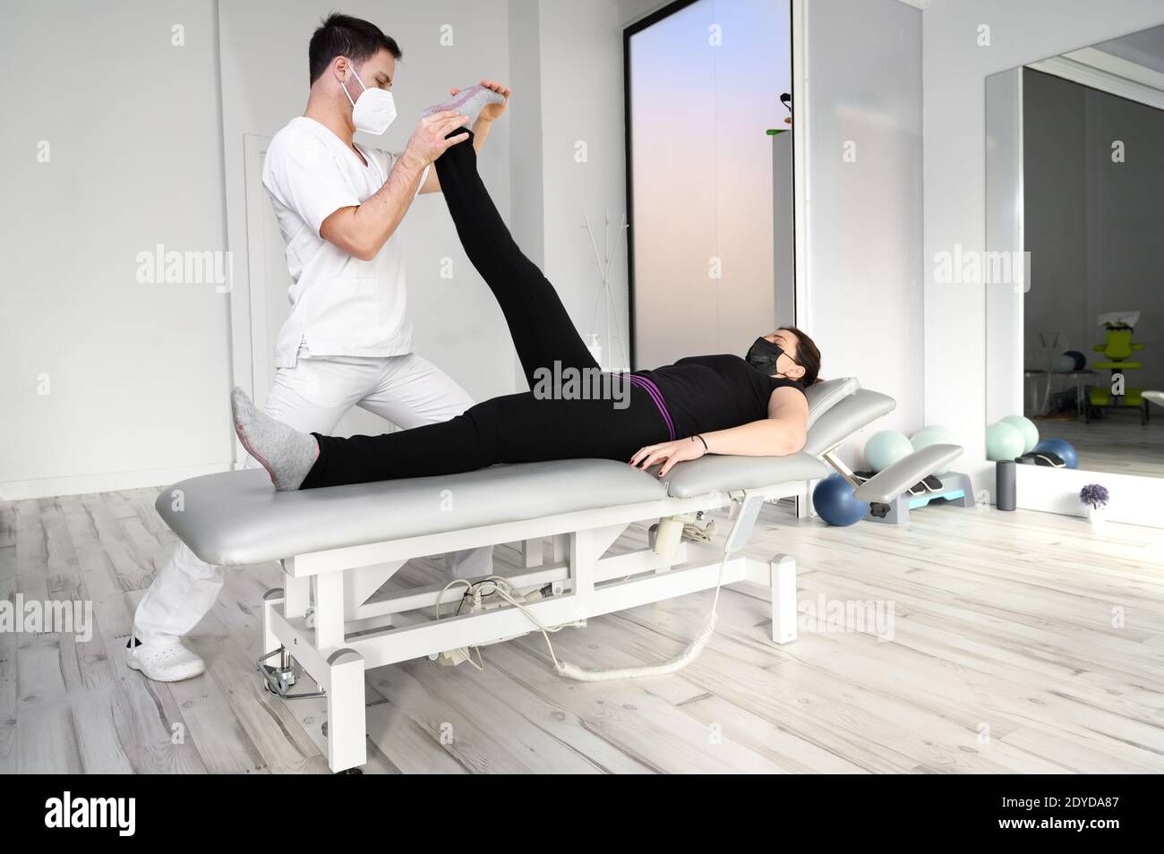 physiotherapist doing leg muscle stretching to female patient. Treatment of a woman's sciatic nerve. High quality photo Stock Photo