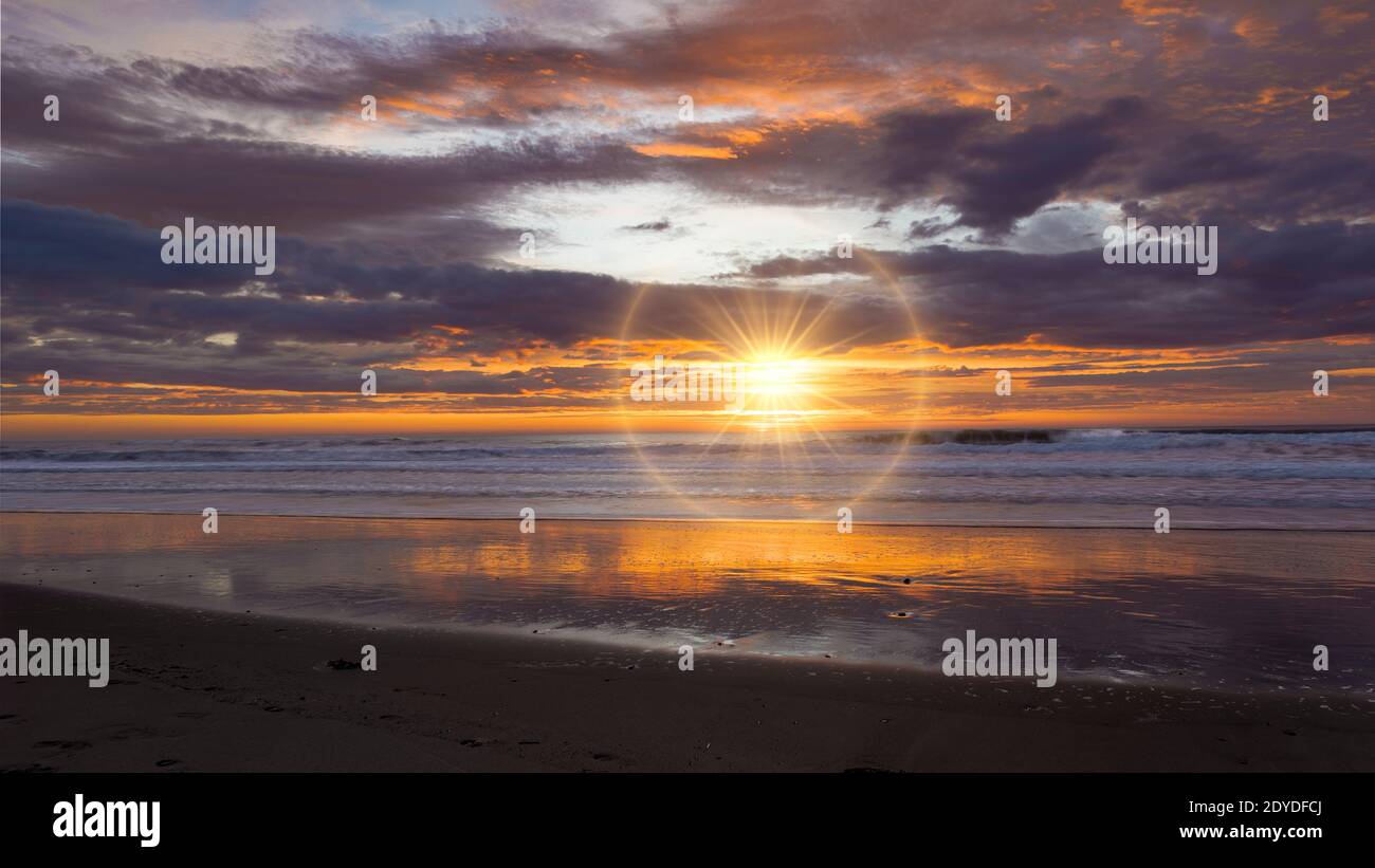 Golden sunrise across the ocean on Wainui Beach New Zealand Stock Photo