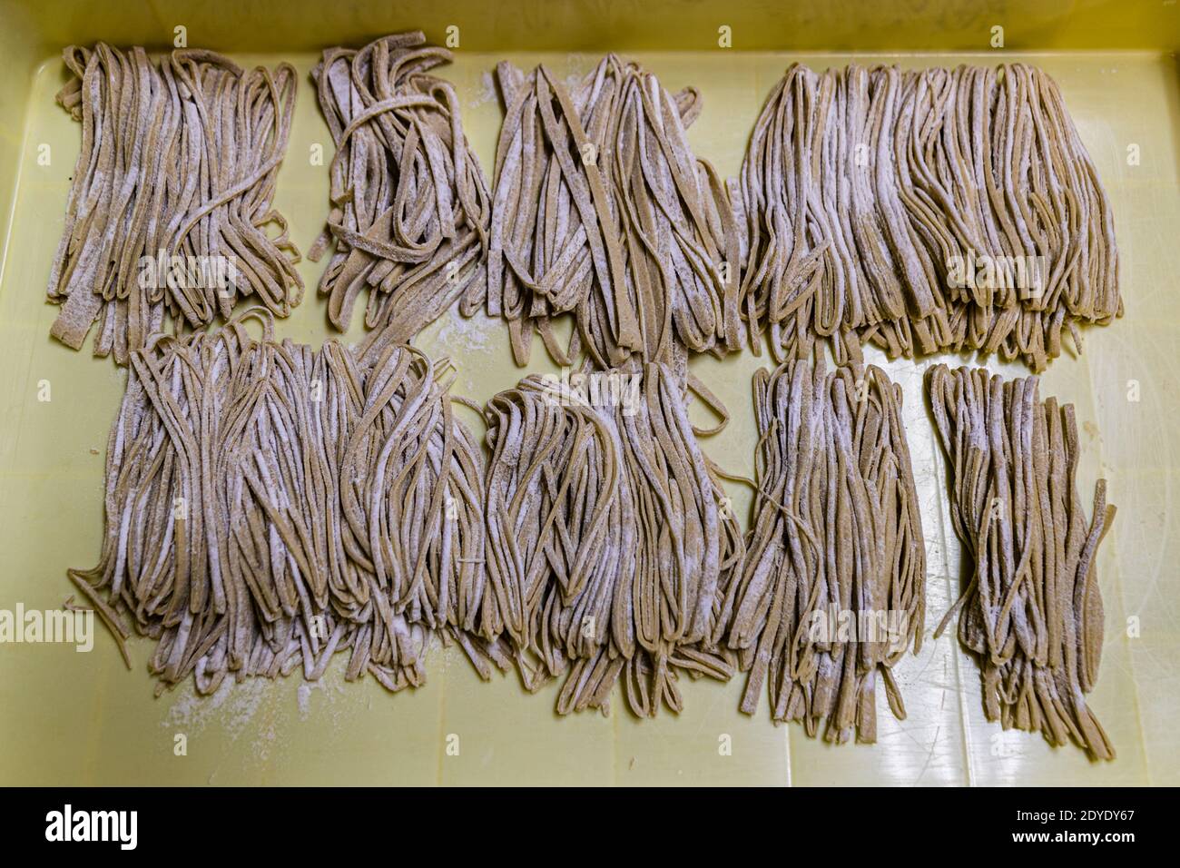 Soba Noodle Preparation in Fujinomiya, Japan. Soba noodles ready for the cooking pot. That an unskilled worker was also at work here can be seen from the strips, some of which are much too thick Stock Photo