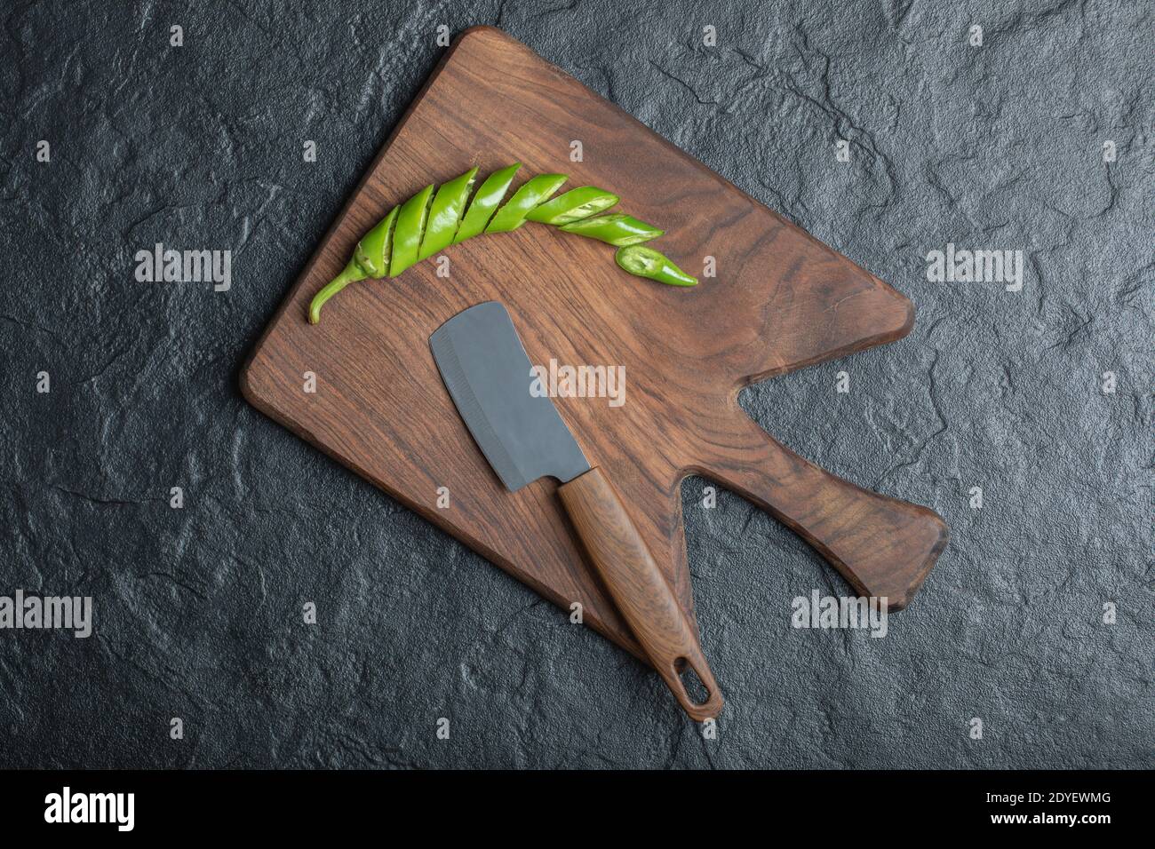 Green sliced hot chili pepper on wooden cutting board Stock Photo