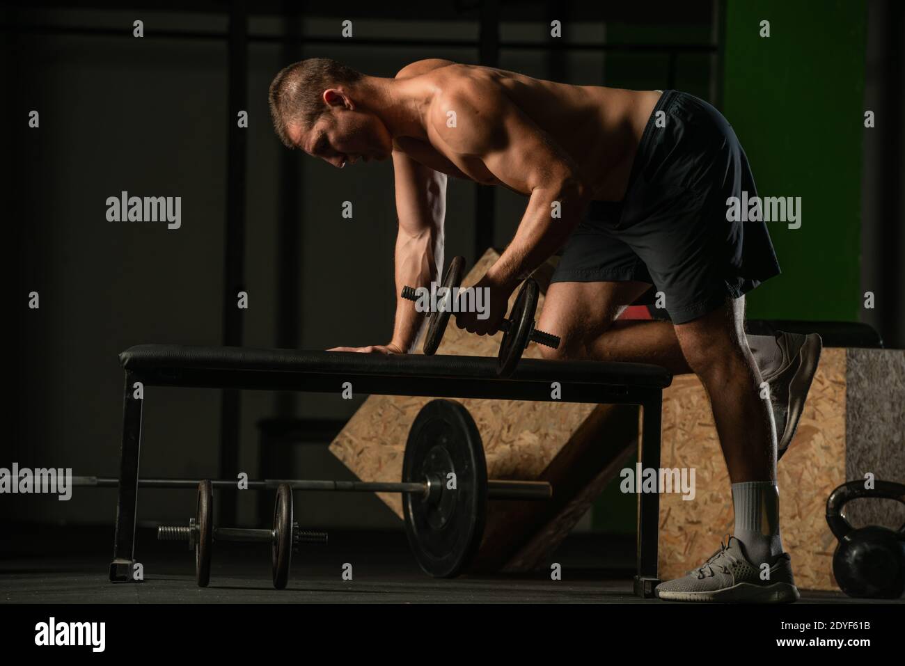Good looking young man doing triceps dumbbell kickback exercises with