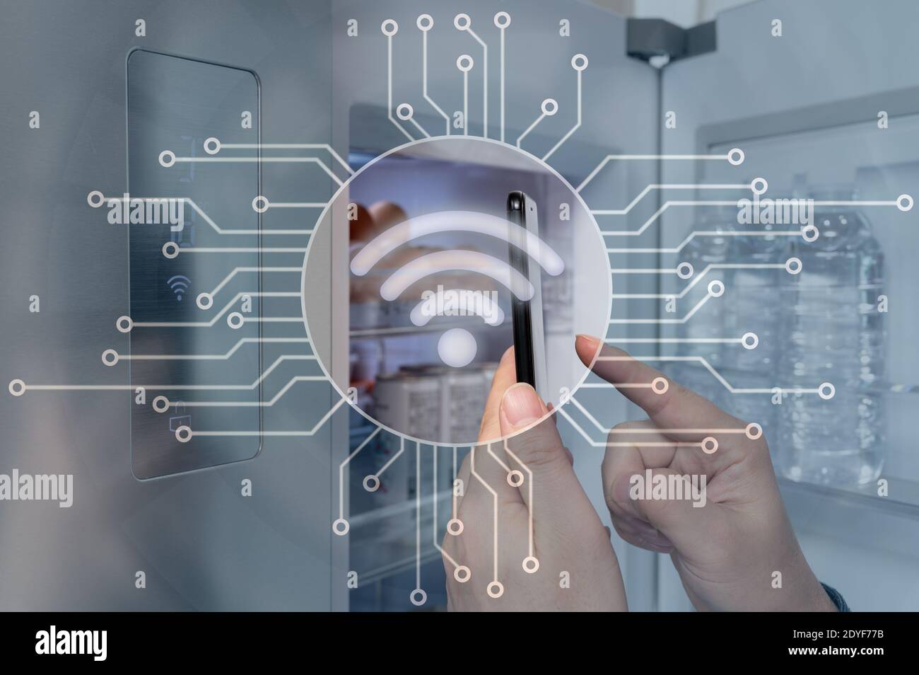 The hand of the man who controls the refrigerator with his smartphone. Internet of Things Concept Stock Photo