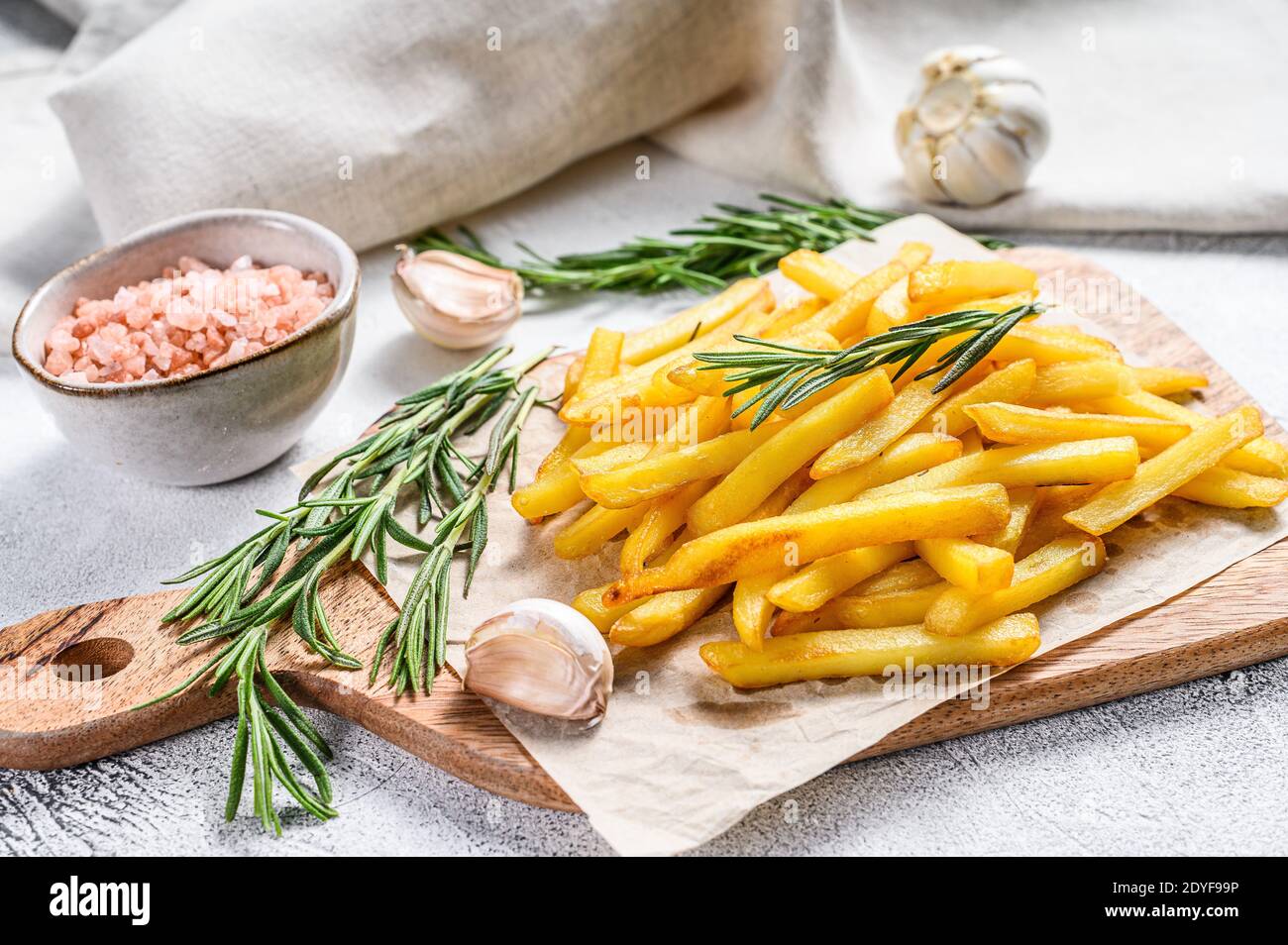 Potatoes fries, French fries with rosemary on a cutting board. White