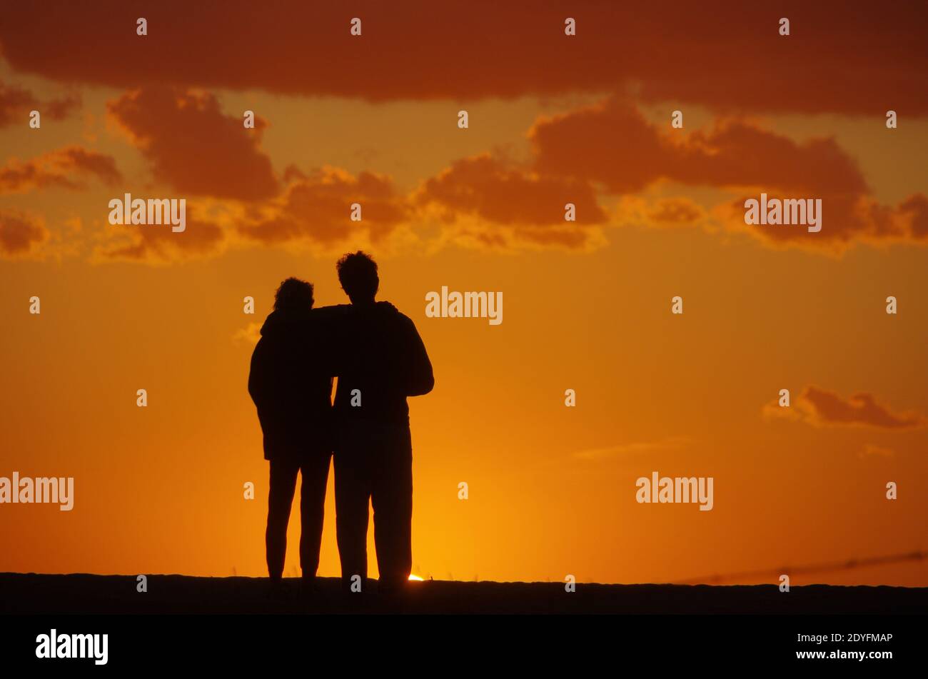 Couple in front of a burning summer evening sky. Silhouettes in the evening light. High quality photo Stock Photo
