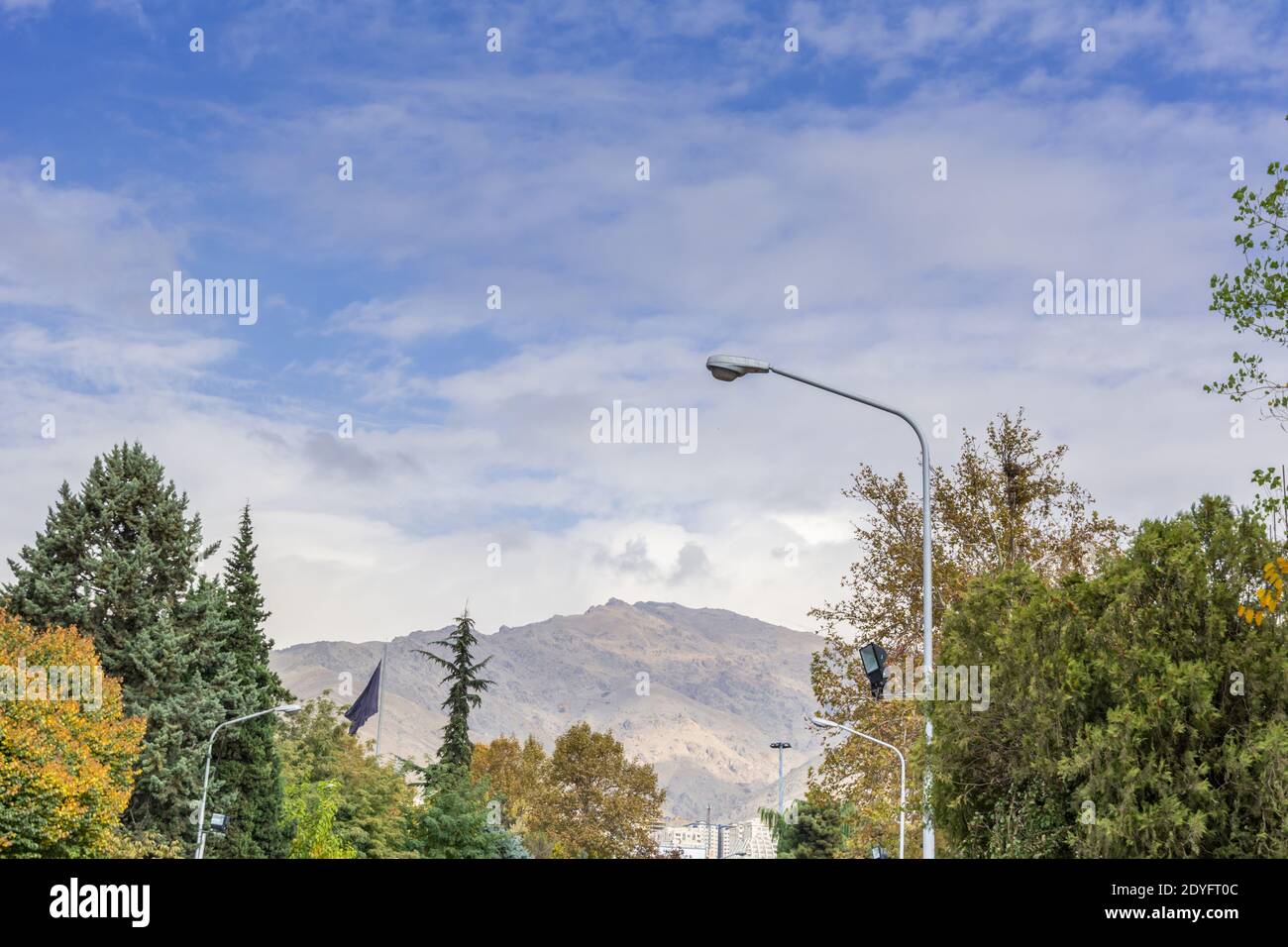 Winter Tehran street view in Tehran International Exhibition Center with snow covered Alborz Mountains against cloudy sky on background Stock Photo