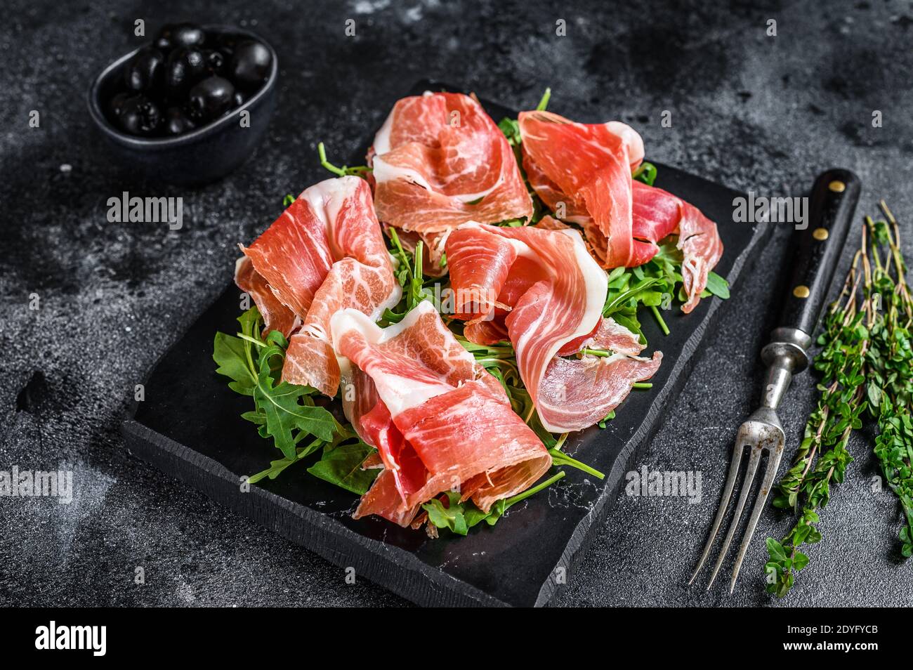 Italian parma prosciutto crudo dried ham on a marble board. Black background. Top view Stock