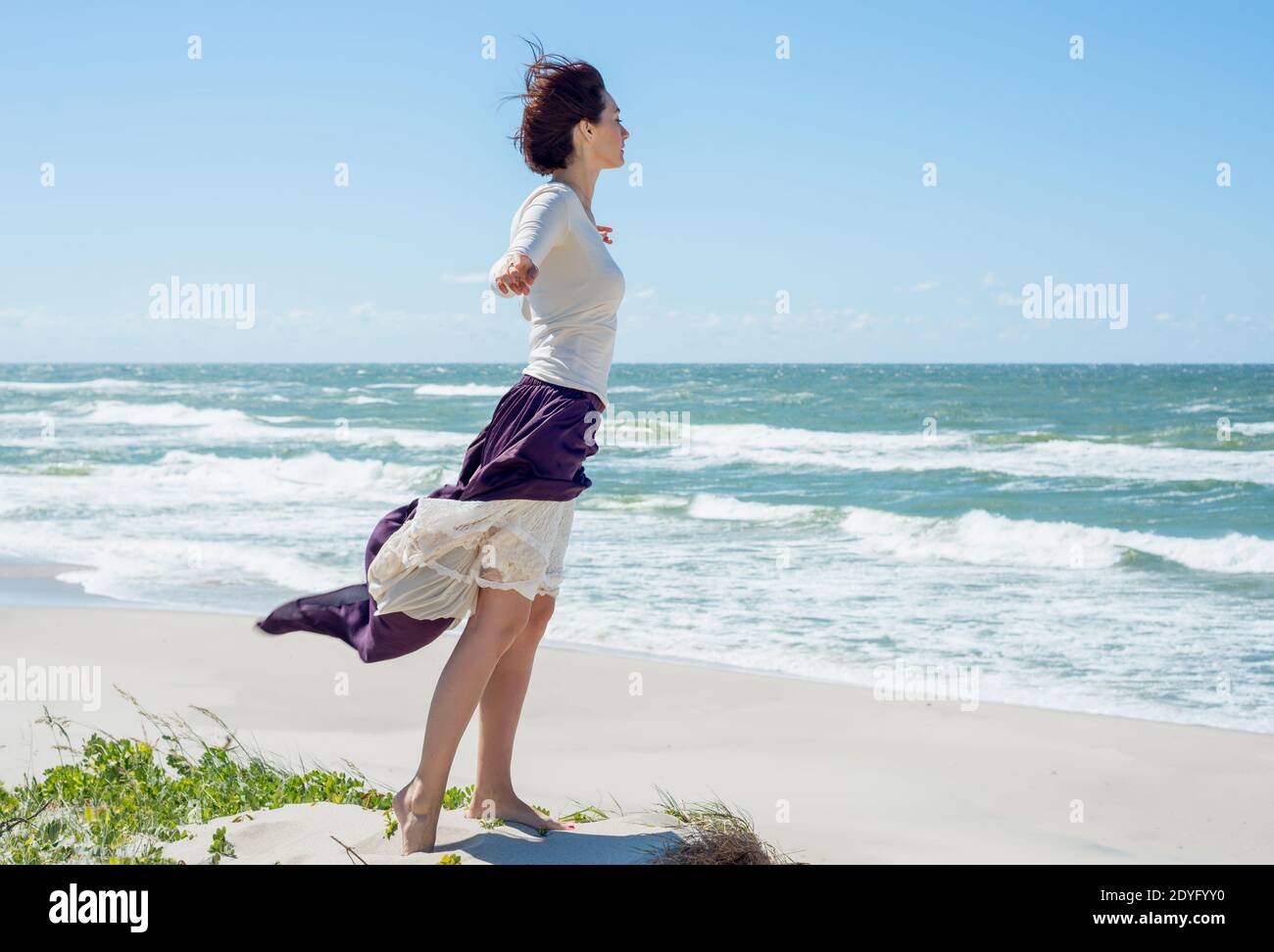 Beautiful brunette woman in a long dress walks along the seashore Stock ...
