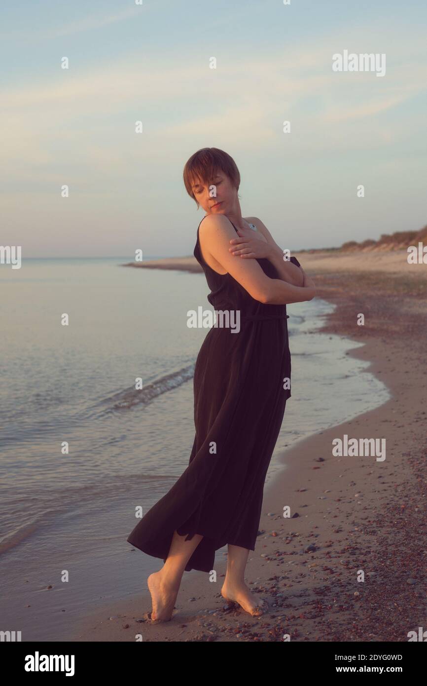 Woman in a black dress is standing on the beach Stock Photo - Alamy