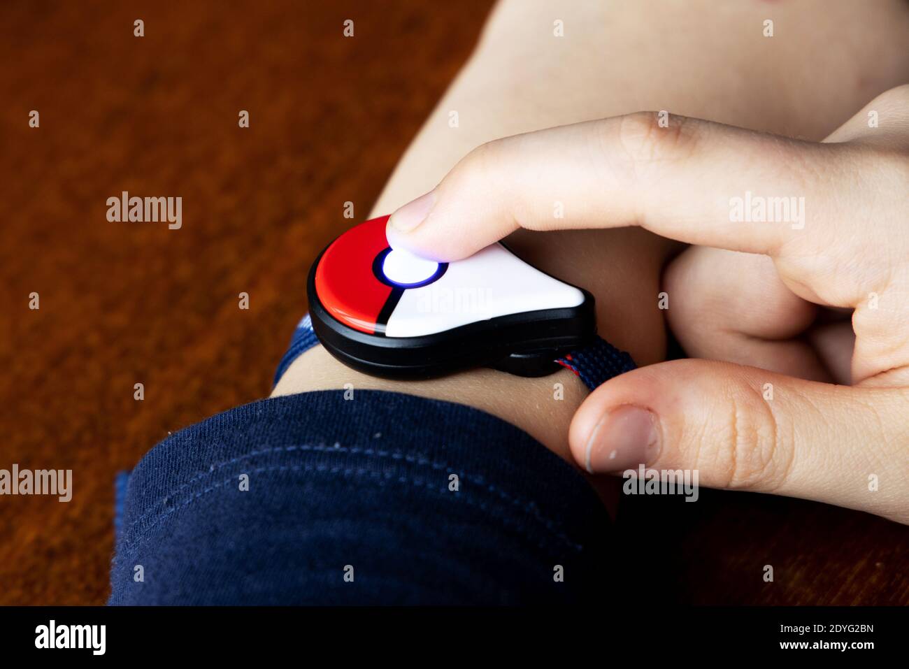 Childs hand with new Japanese game Pokemon go plus made by The Pokemon company Nintendo. Addictive popular activity among children and grownups. Stock Photo