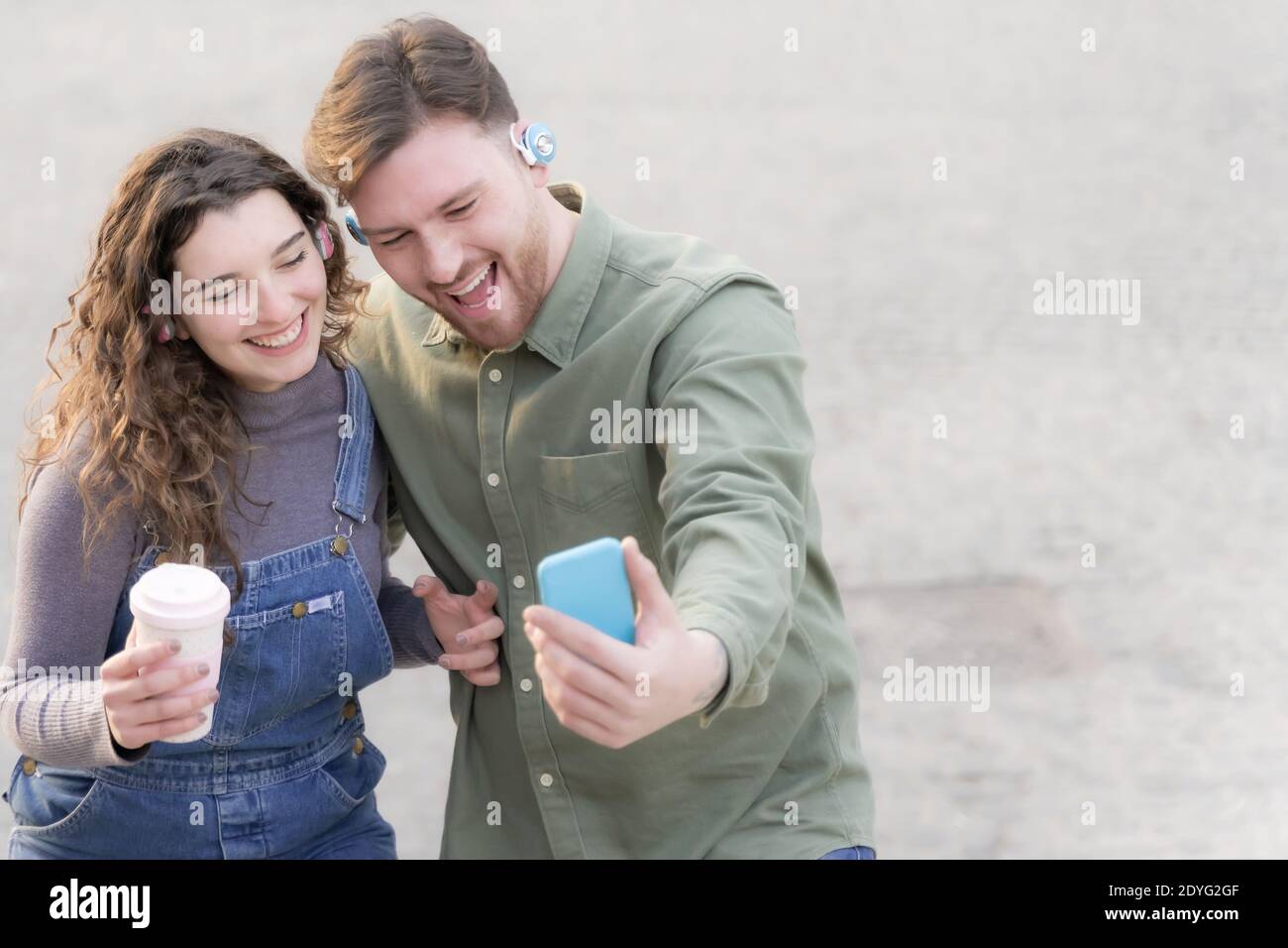 Happy couple listening music and making a selfie. Millennial friends drinking a good smoothie and using new technology. Stock Photo