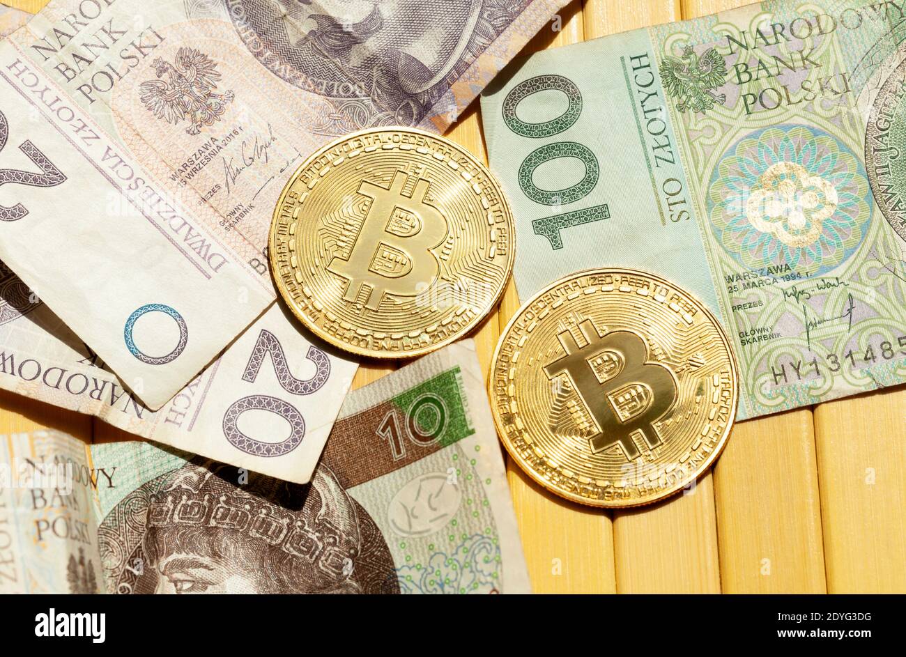 Bitcoin golden coins and Polish zloty bills, money closeup. Cash and cryptocurrency laying on