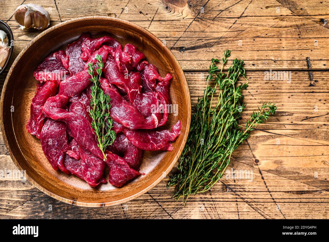 Raw uncooked beef meat sliced in strips with fresh herbs for beef