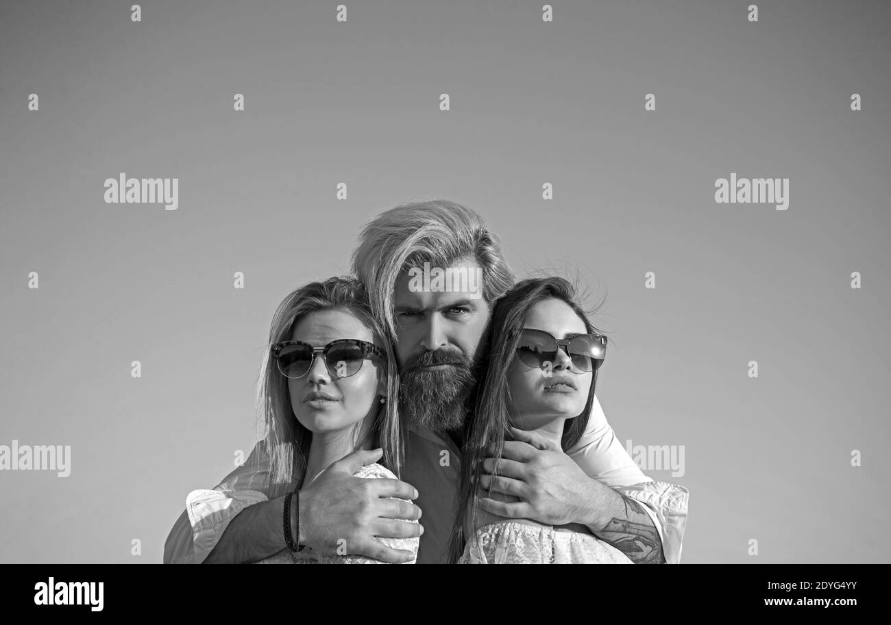 Portrait of happy man between two girls standing on sky background on summer vacation Stock Photo