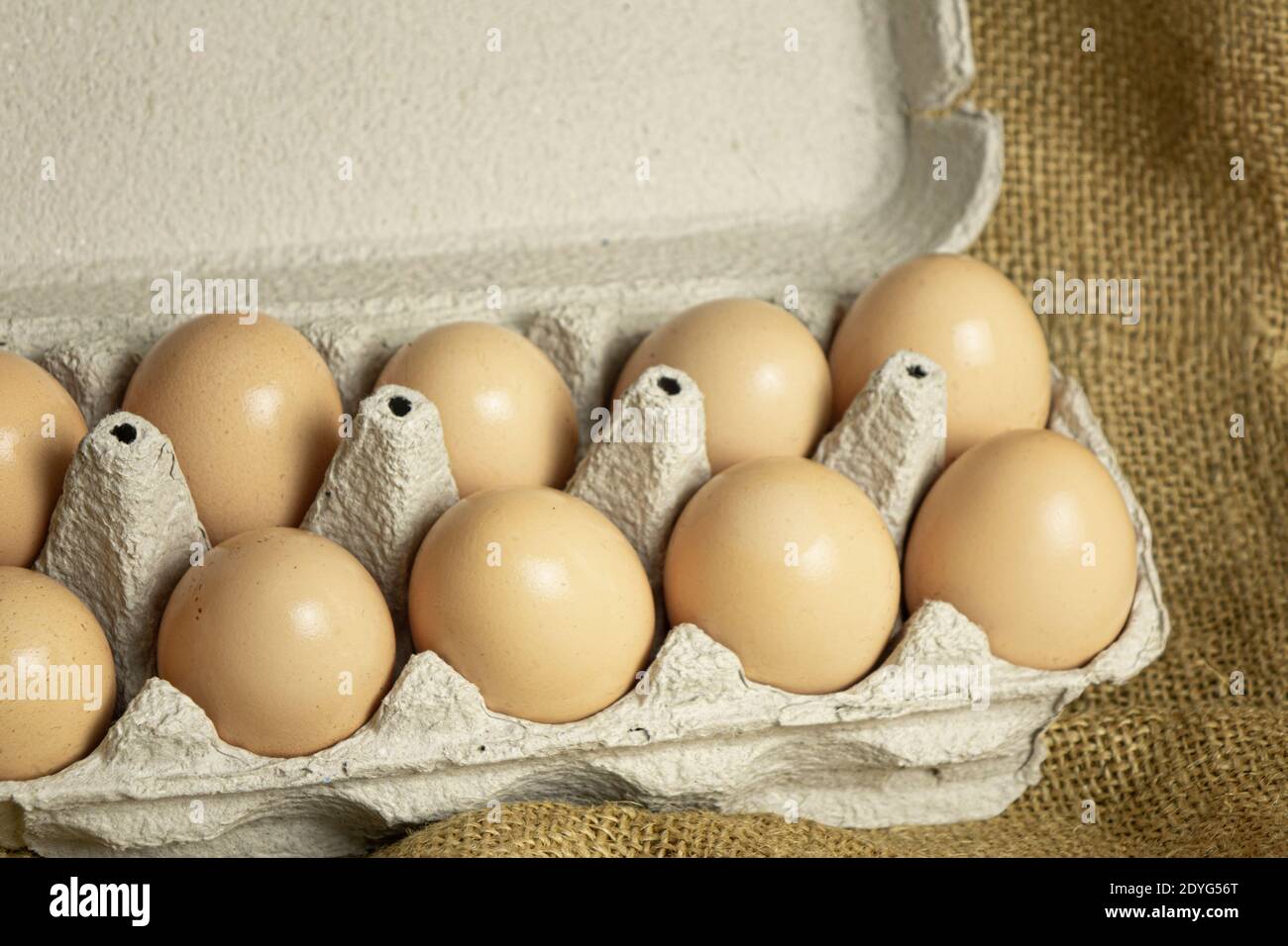 paper box with farm fresh chicken eggs on sackcloth background Stock Photo