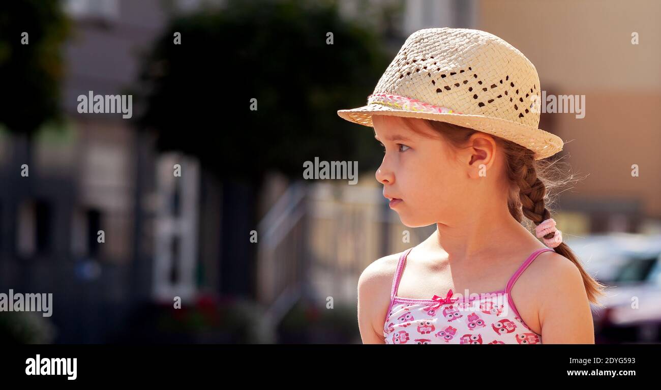 Little girl alone, school age child model looking right, copy space, text space on left, caucasian kid wearing panama hat, summer summertime travel Stock Photo