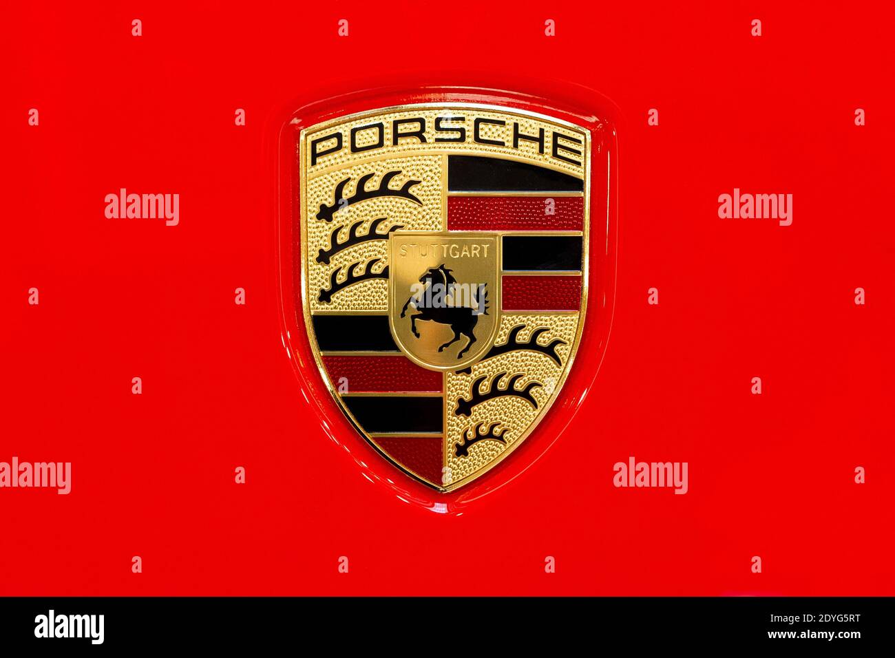 Porsche car brand logo on a shiny red car hood closeup, macro, detail, top view, classic Porsche AG Stuttgard company emblem isolated, logo from above Stock Photo