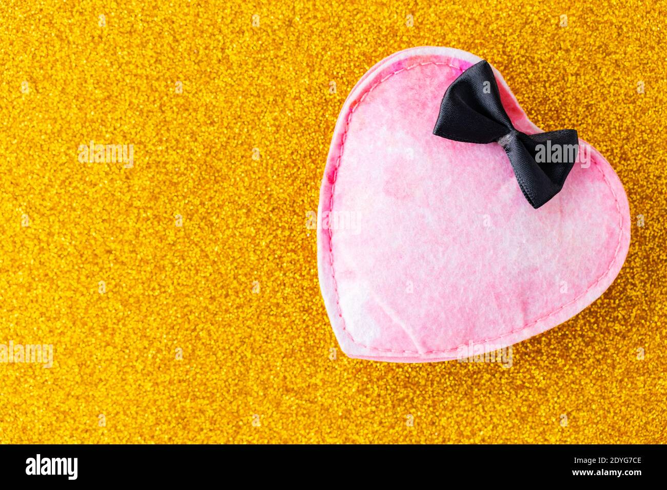 Pink felt heart on golden glitter background. Felt heart with 