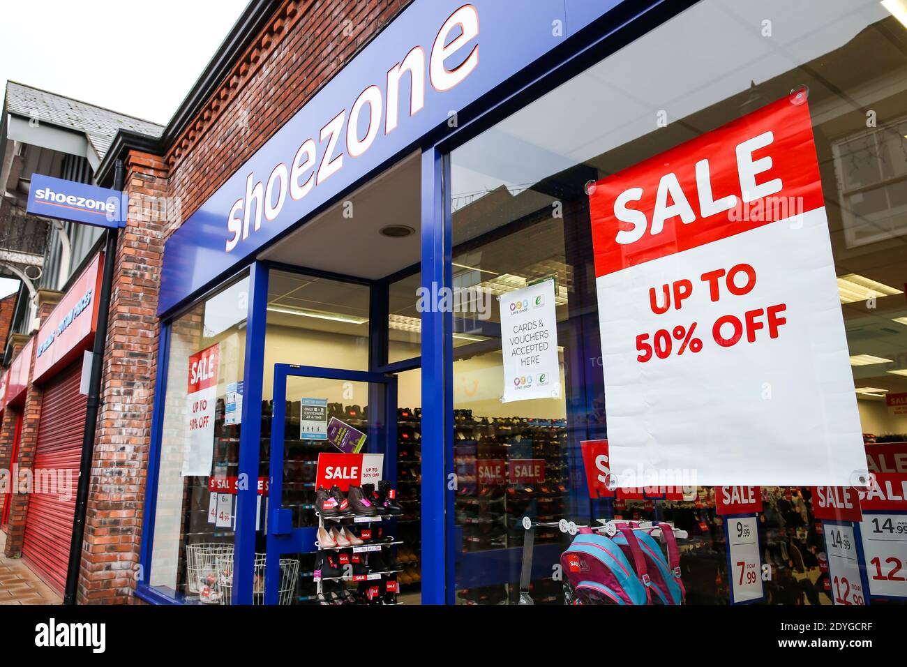 Sale posters in the window of Shoezone in Newcastle-under-Lyme, Staffordshire, during the Boxing Day sales. Boxing Day spending is expected to fall by more than a quarter compared with a year ago, after extensive new Covid-19 restrictions forced non-essential retailers to close. Stock Photo