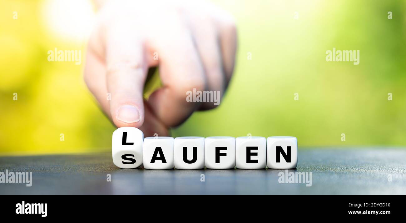 New year resolution. Hand turns dice and changes the German word saufen  (booze) to laufen (running Stock Photo - Alamy