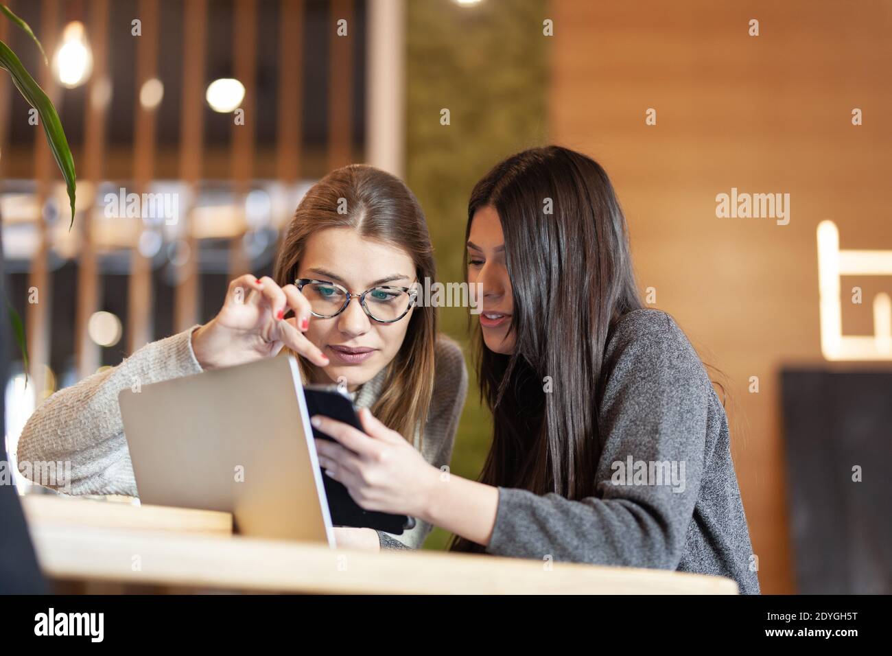 two girls in a cafe with a tablet and laptop Stock Photo - Alamy