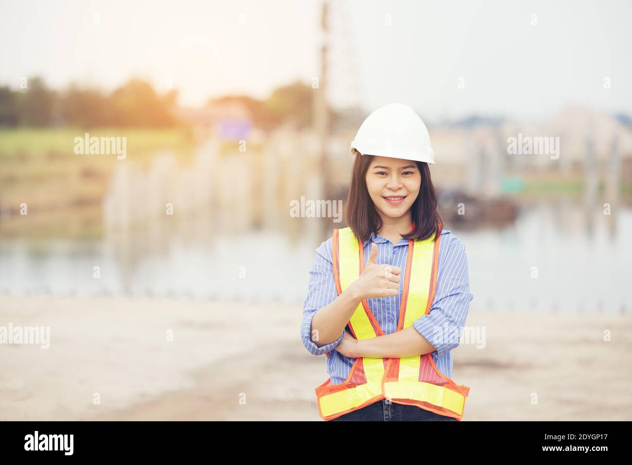 Female engineer with helmet showing thumb up as ok sign at construction site. Power of women, Gender equality, Working women, Confident Female Enginee Stock Photo