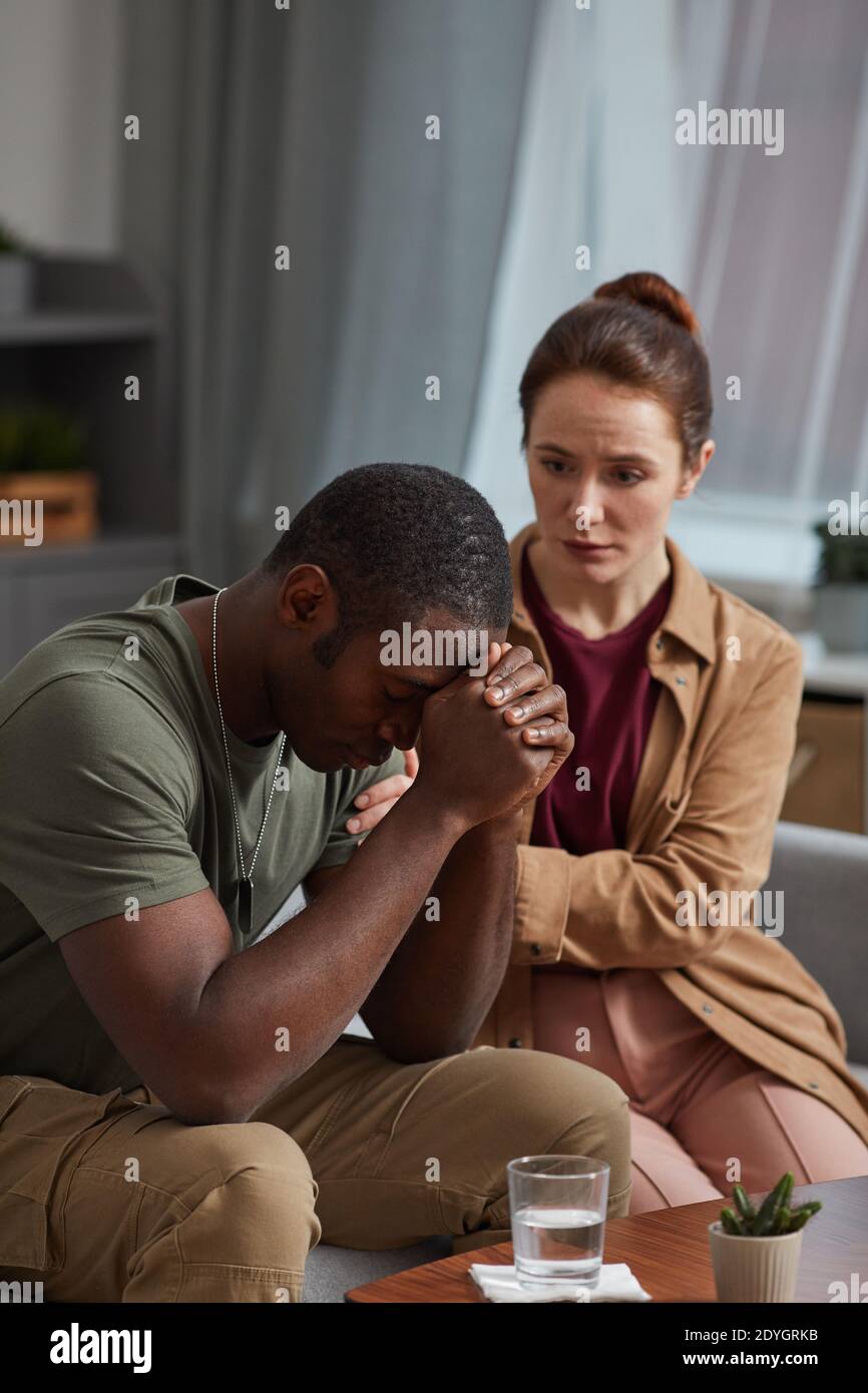 African man worried about his problems with woman sitting near by and supporting him Stock Photo